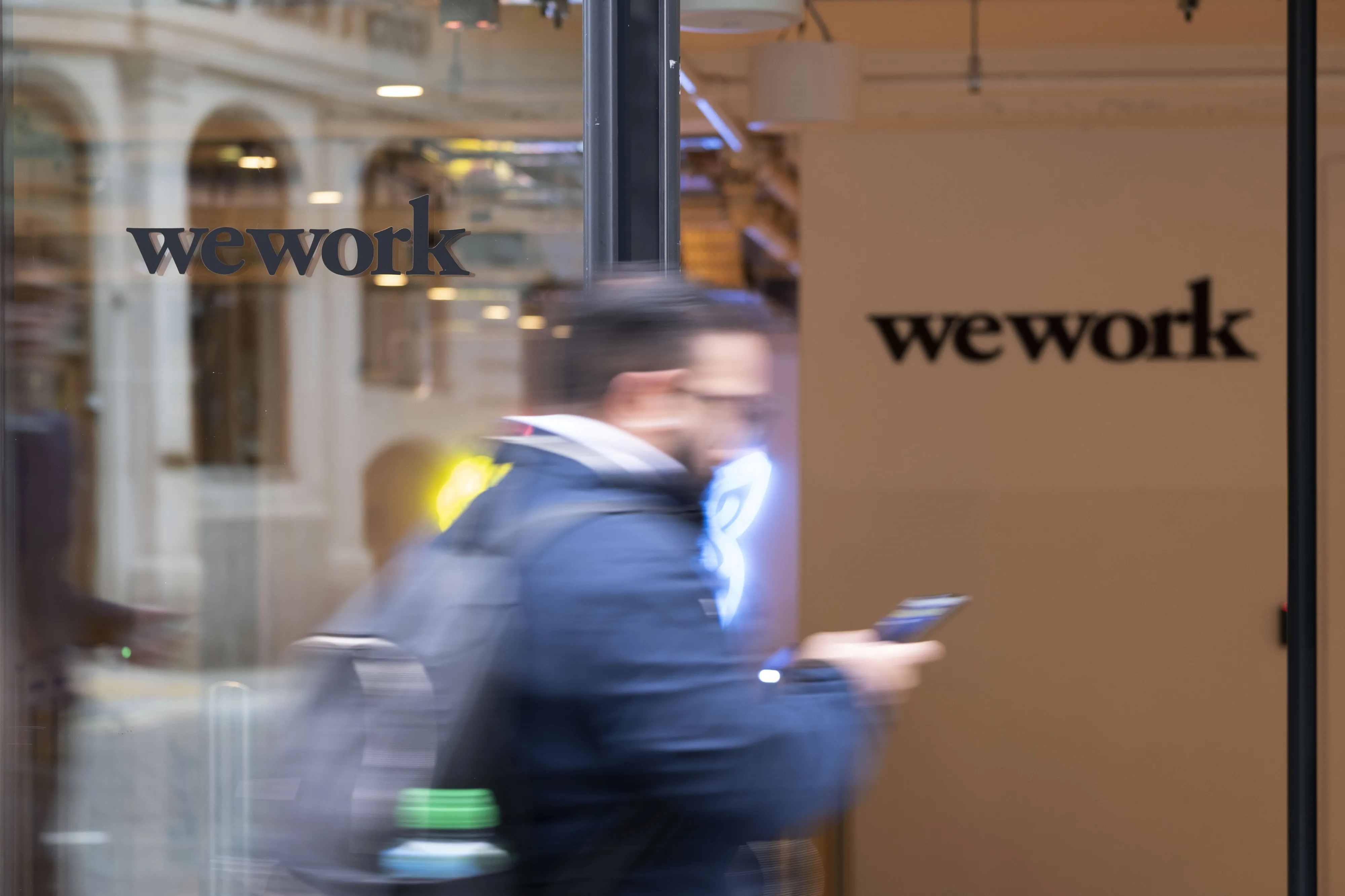 A pedestrian walks past the entrance to a We Work co-working office space.