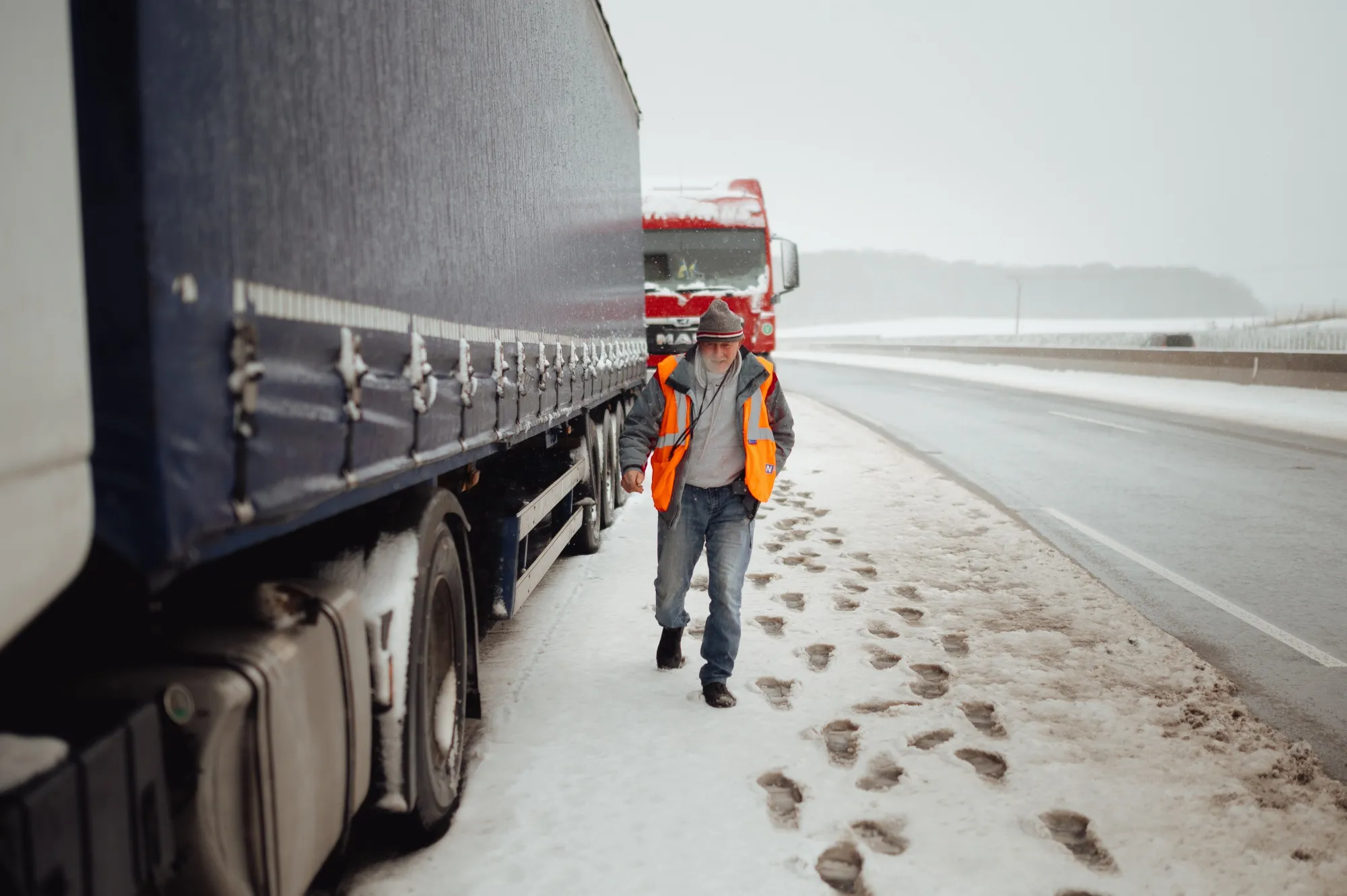 A truck driver walks past his snow covered truck that has been standing in a long queue of vehicles for over 10 days now near Bidovce, Slovakia.