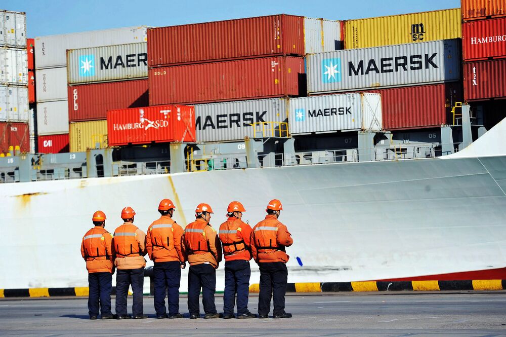 Workers stand in line next to a container ship at a port in Qingdao in China's eastern Shandong province.