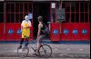 A server wearing a protective mask and face shield talks to a cyclist outside a restaurant in the Vila Madalena neighborhood of Sao Paulo, Brazil.