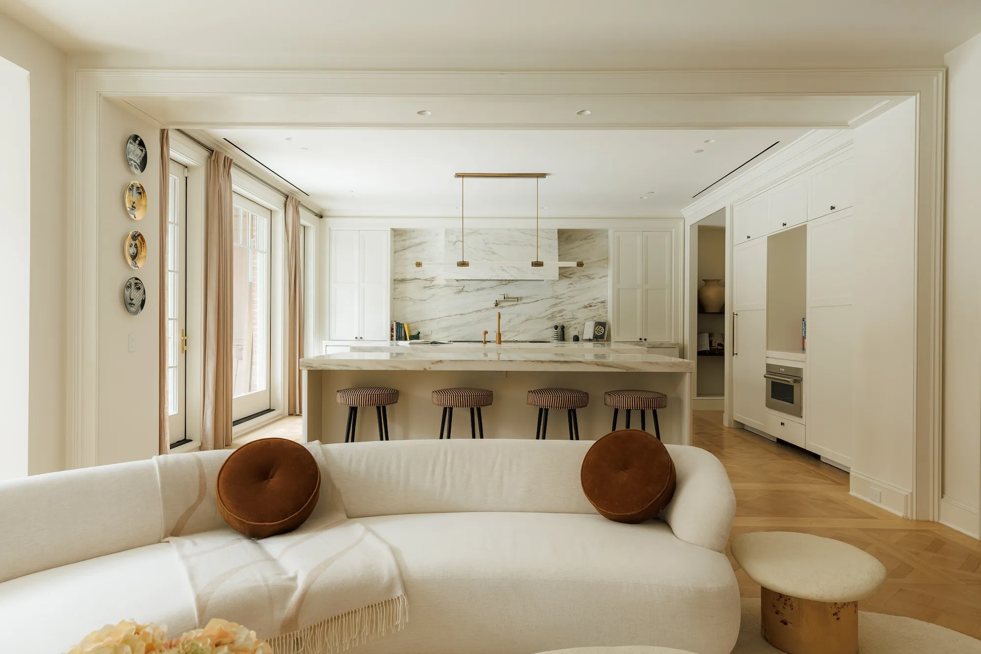 An open-plan kitchen with white marble island, built-in cabinets and a white sofa.