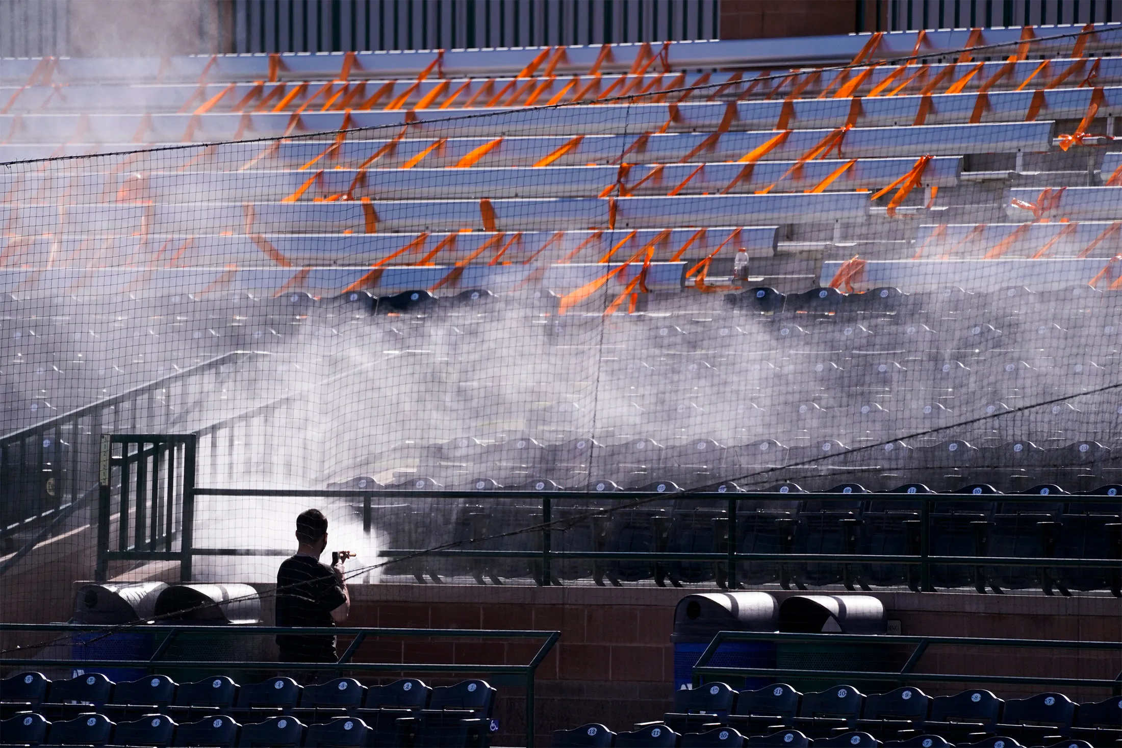 A worker cleans seats taped off for social distancing ahead of a game between the San Francisco Giants and the Los Angeles Angels at Scottsdale Stadium on Feb. 26.