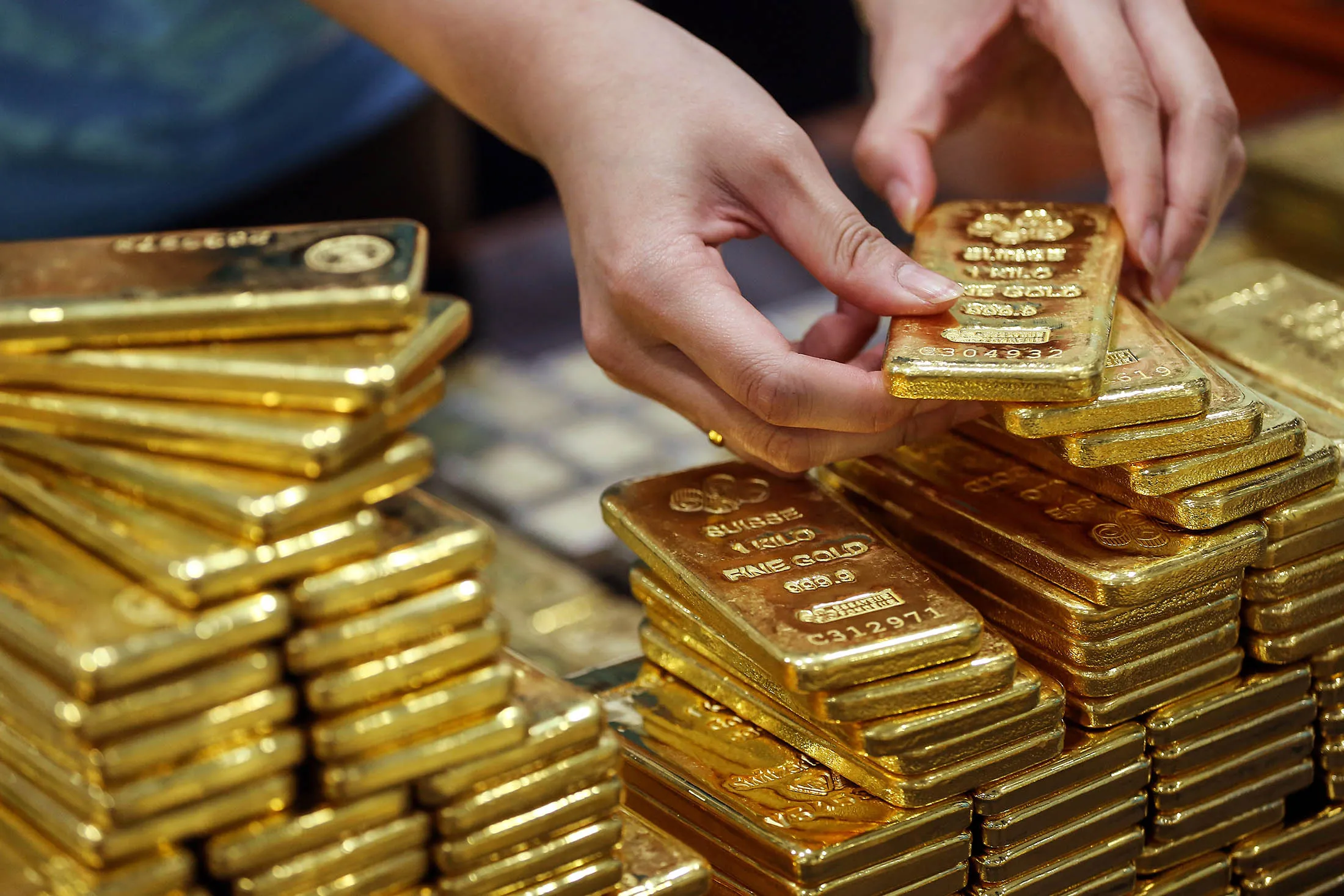 An employee arranges one kilogram gold bars.
