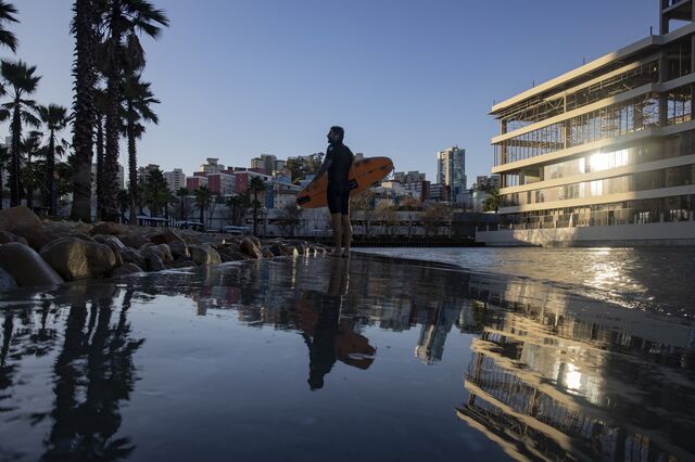 A surfer holding a board is reflected in the surf pool at the Sao Paulo Surf Club . 