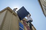 Contractors move a SunRun&nbsp;solar panel up a ladder to the roof of a new home&nbsp;in Sacramento, California.