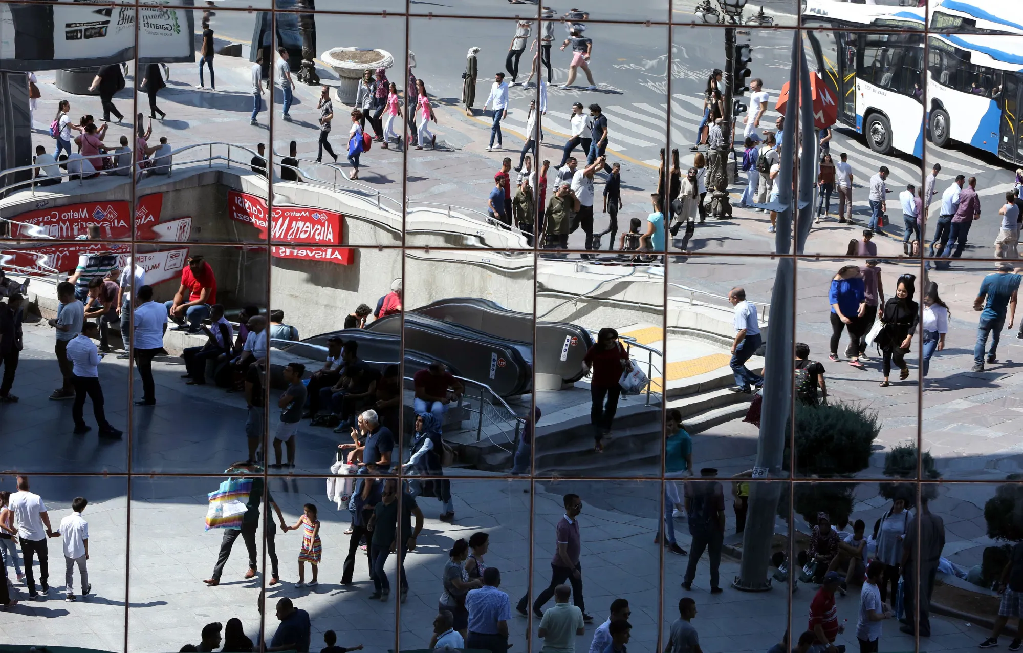 Mirrored windows reflect pedestrians on Mustafa Kemal Ataturk street in Ankara.