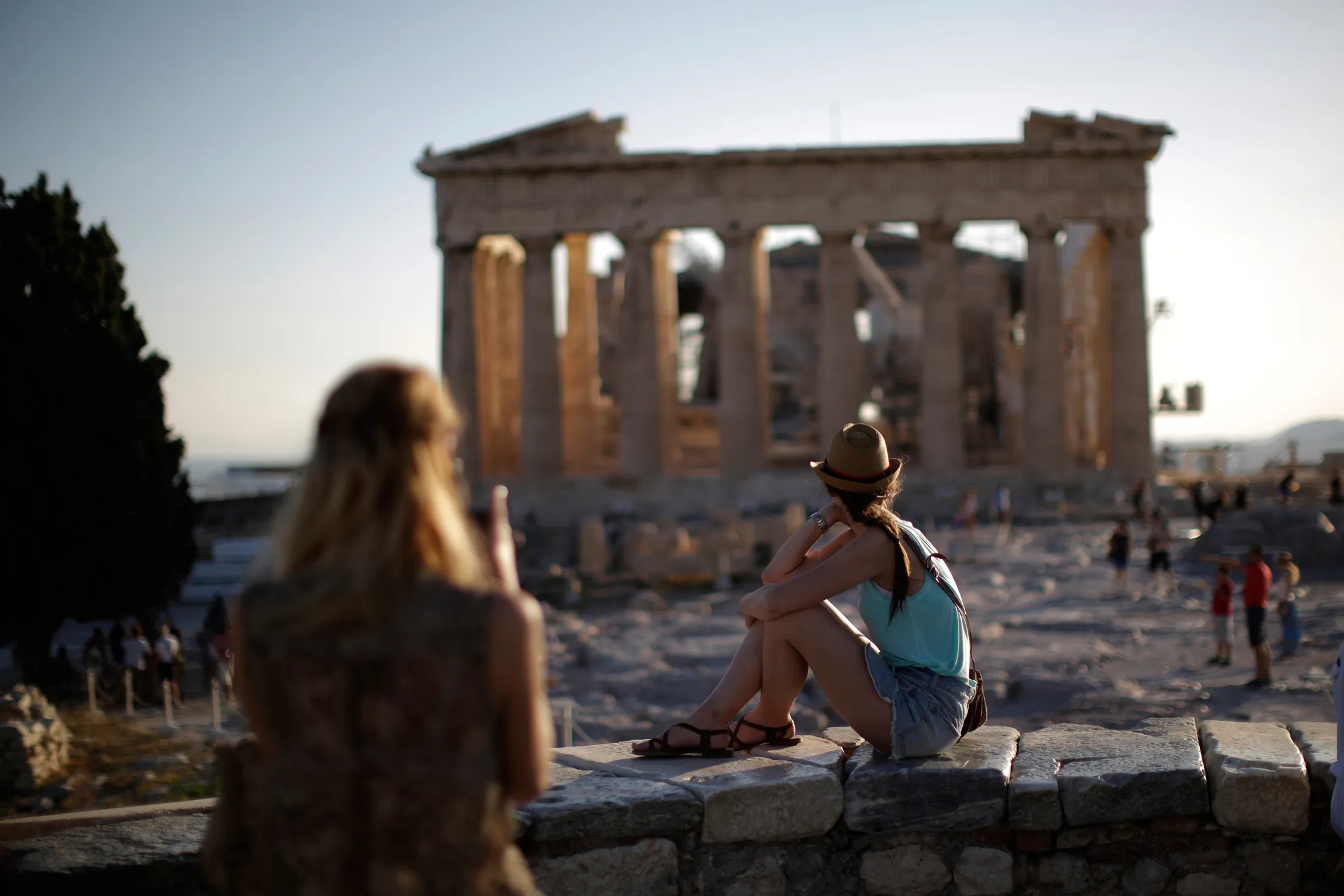 Tourists observe the Parthenon temple ruins on Acropolis Hill at sunset in Athens, on July 20.
