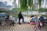People gather around a lake at a park in Beijing.