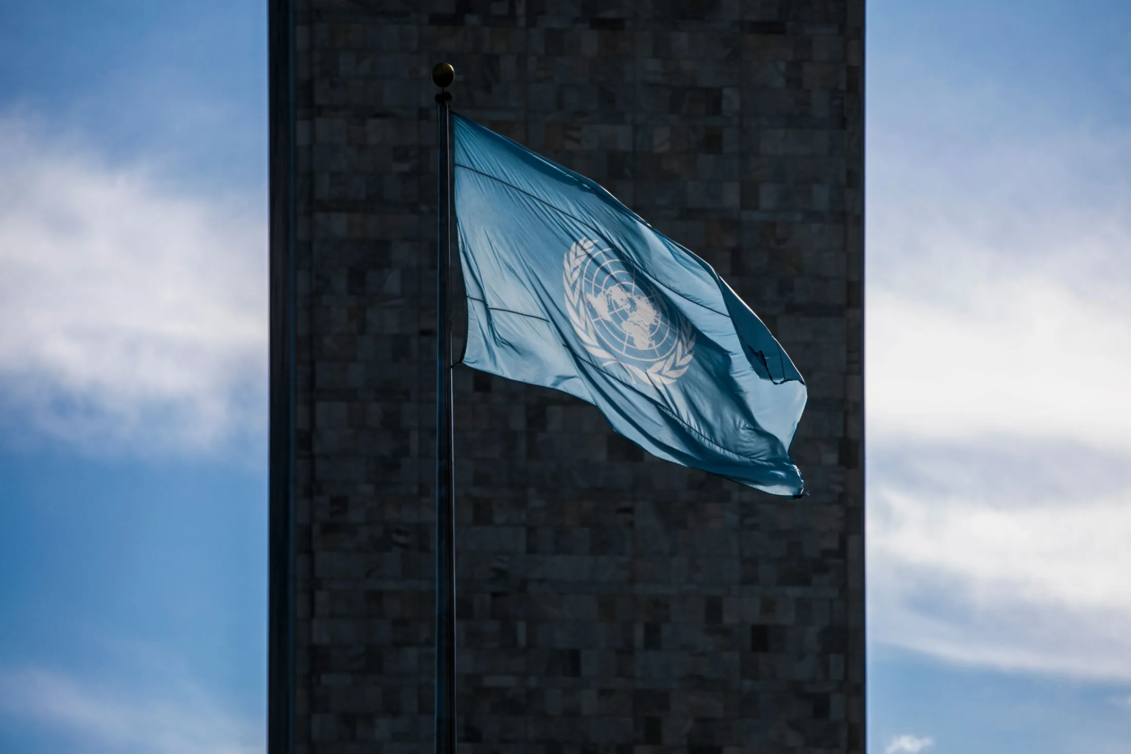 The flag of the United Nations in front of the UN building in New York.