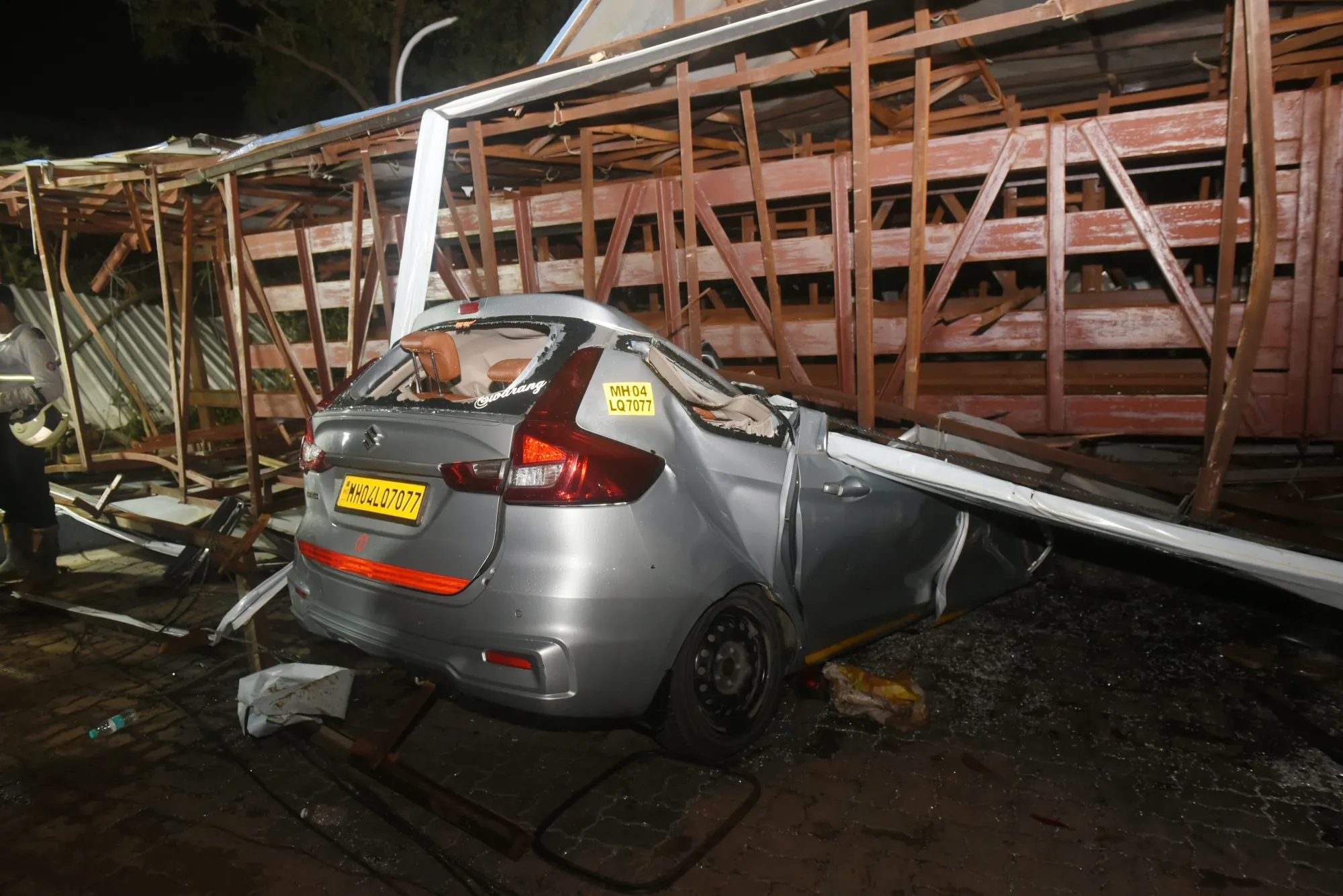 A car crushed by the collapsed structure of a billboard and metal girder a petrol station in Mumbai on May 13.