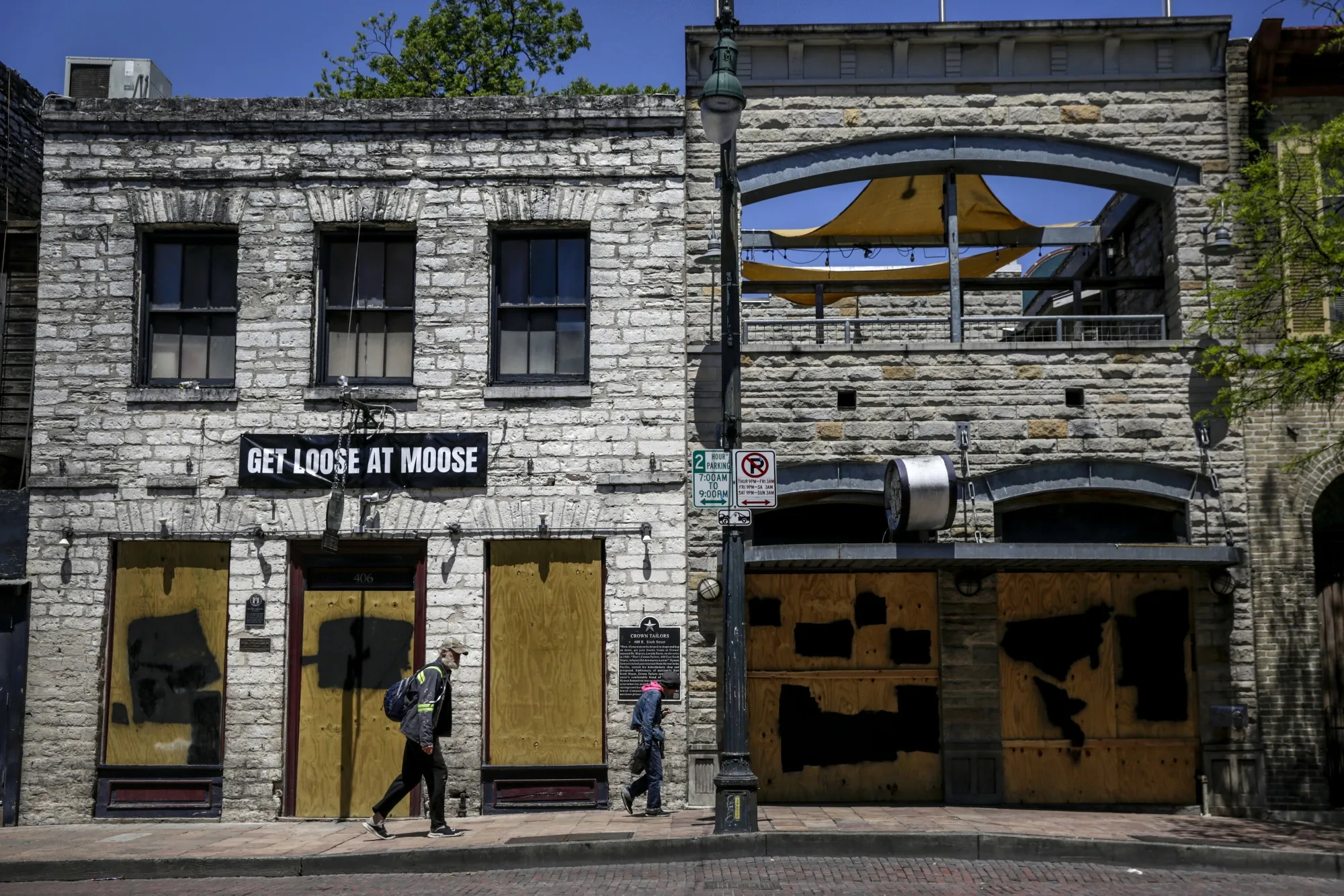 Pedestrians walk past boarded up restaurants on East Sixth Street in downtown Austin, Texas on April 13.
