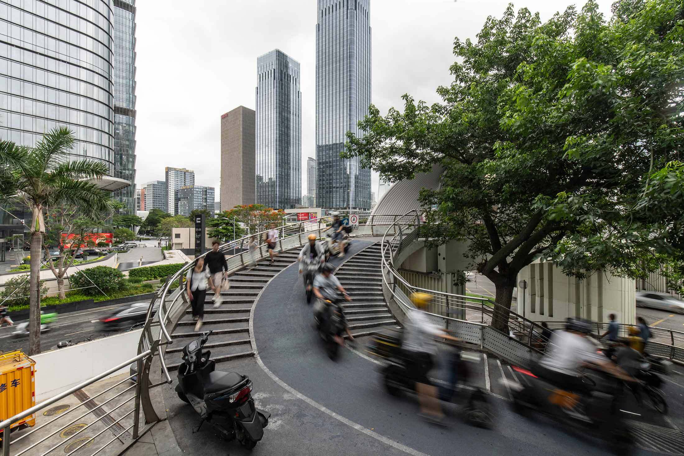 Pedestrians and cyclists at a bridge-crossing over a large highway in Shenzhen.