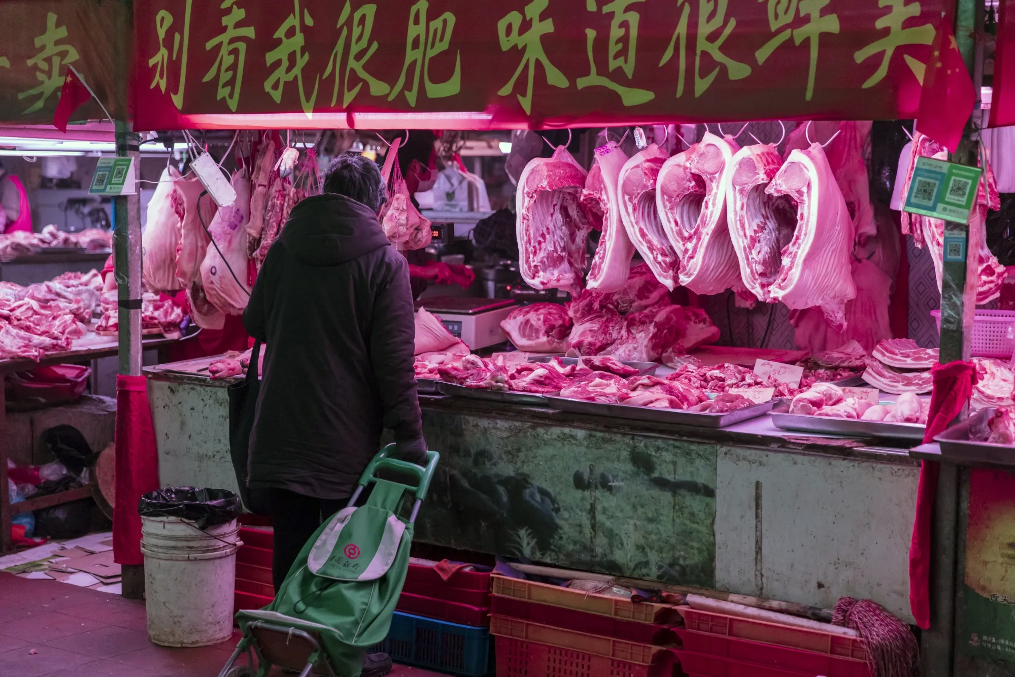 A customer buys pork at a market in Shanghai, China.