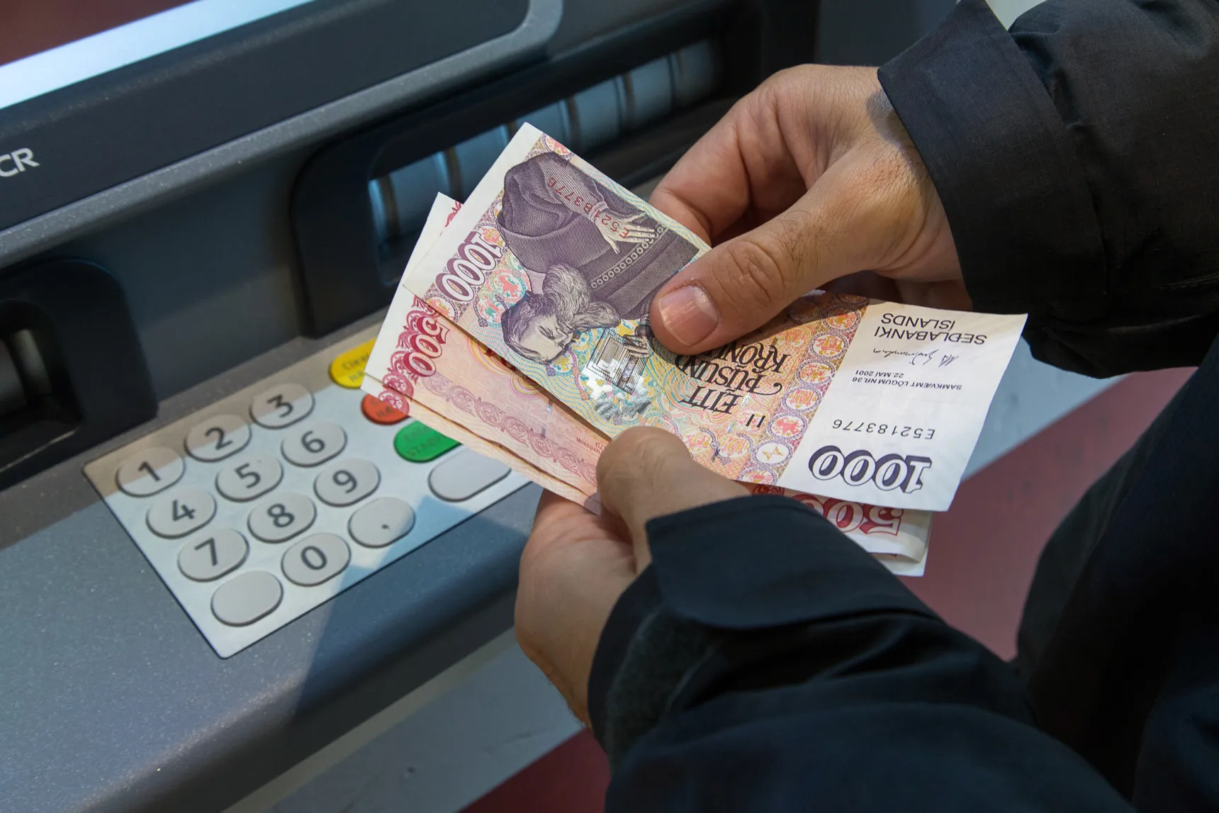 A customer collects Icelandic krona banknotes from an automated teller machine (ATM) in Reykjavik, Iceland.

