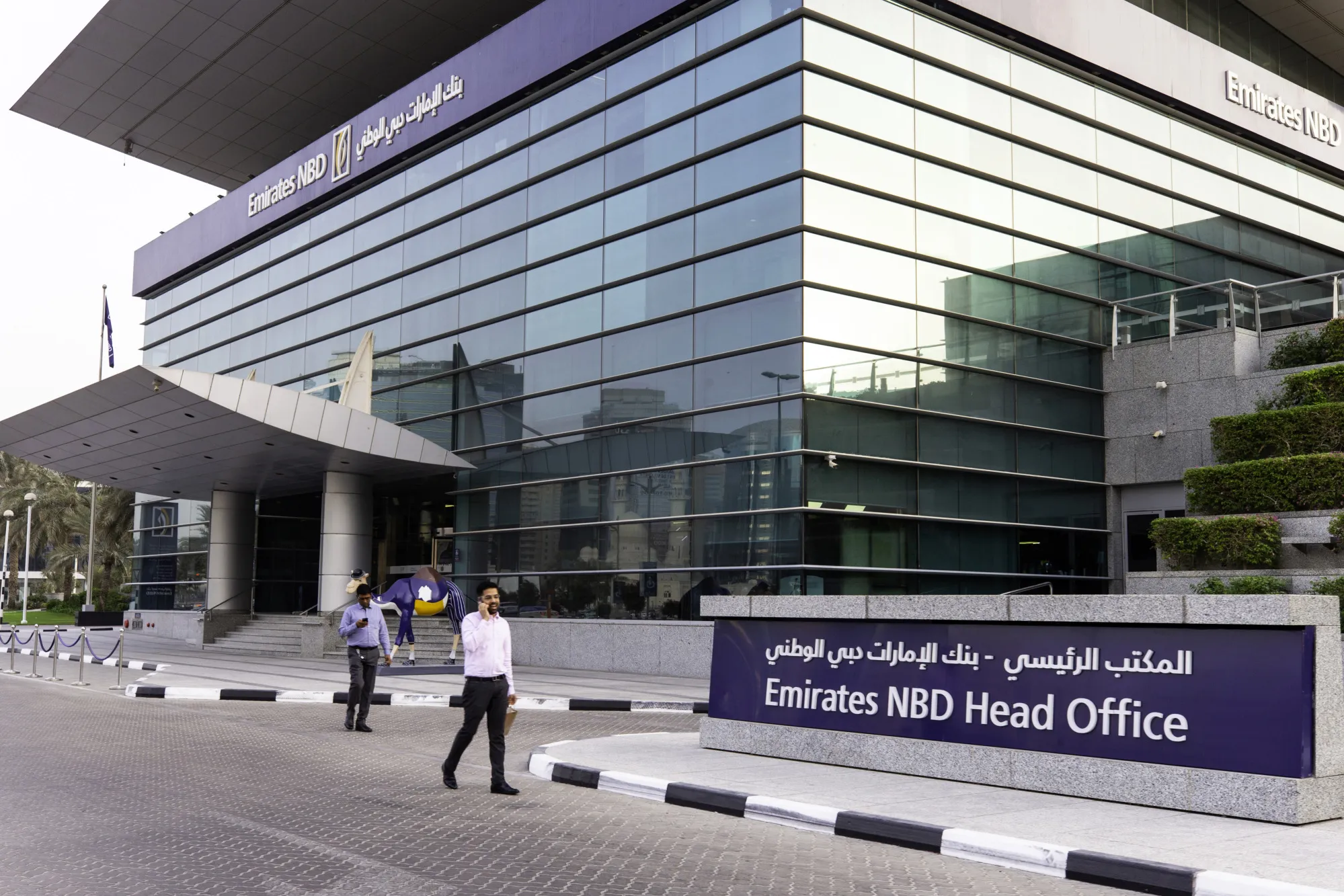 Pedestrians walk near the entrance to the main office for the Emirates NBD PJSC bank in Dubai.