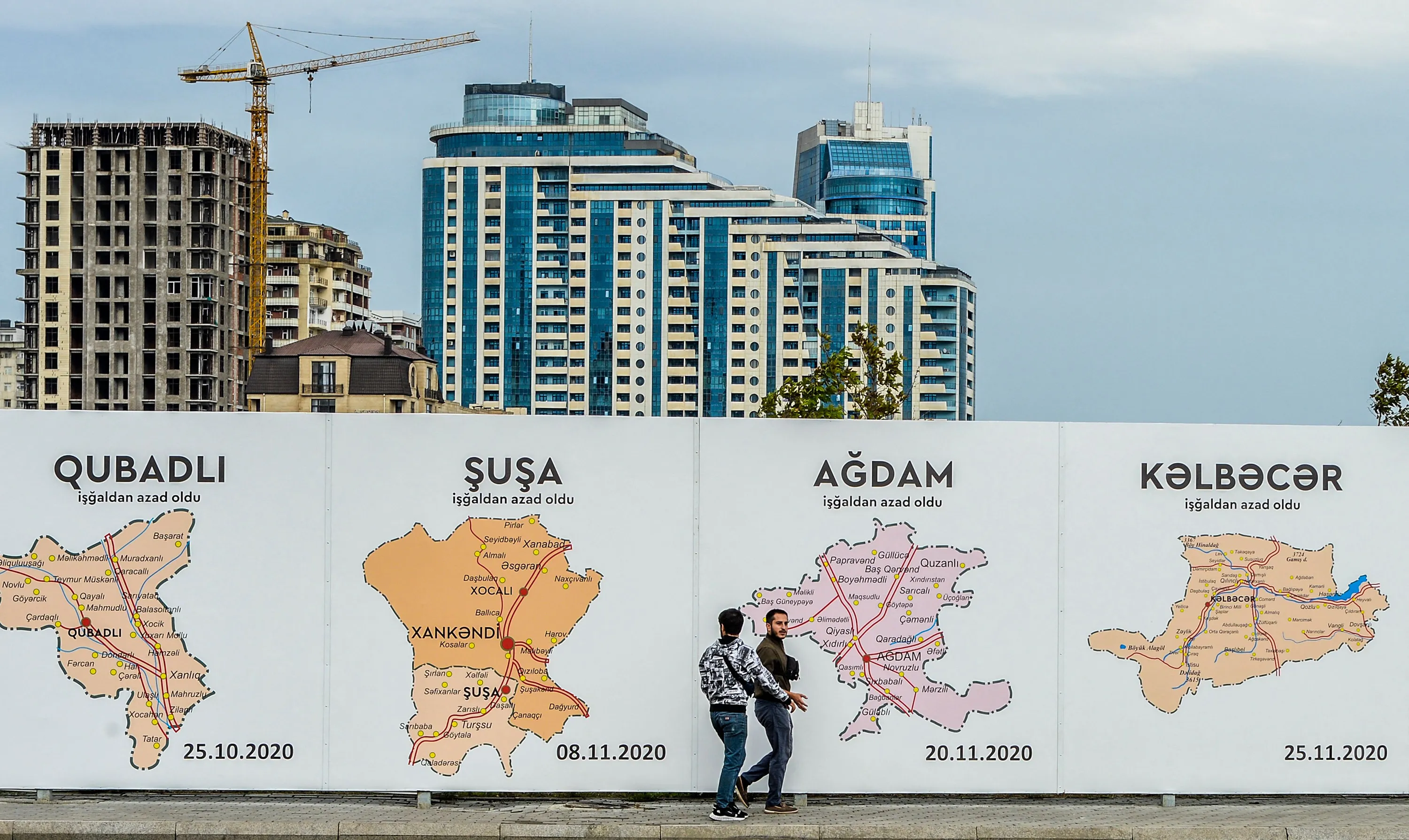 People walk past a poster showing maps of the towns of Nagorno-Karabak, in Baku, Azerbaijan, on Sept., 13.