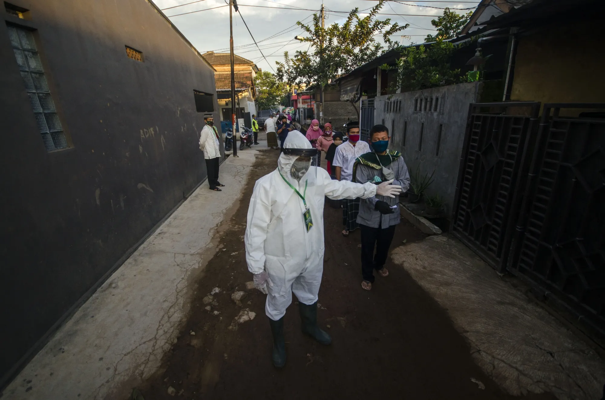 An officer in protective suit guides people to maintain social distance before performing Eid al-Fitr prayer in West Java, May 24.