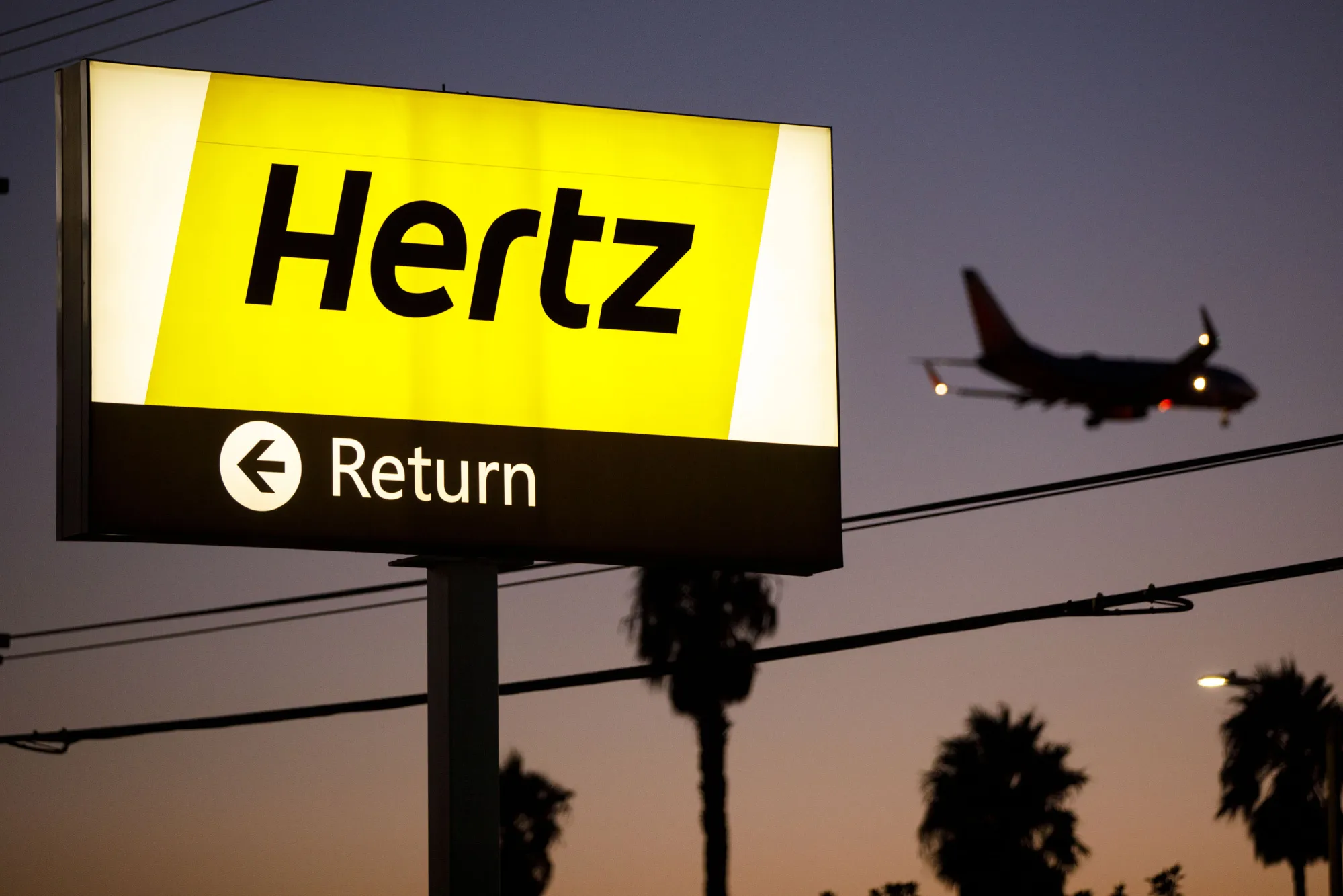 A plane flies above&nbsp;a Hertz Global Holdings Inc. location at Los Angeles International Airport.