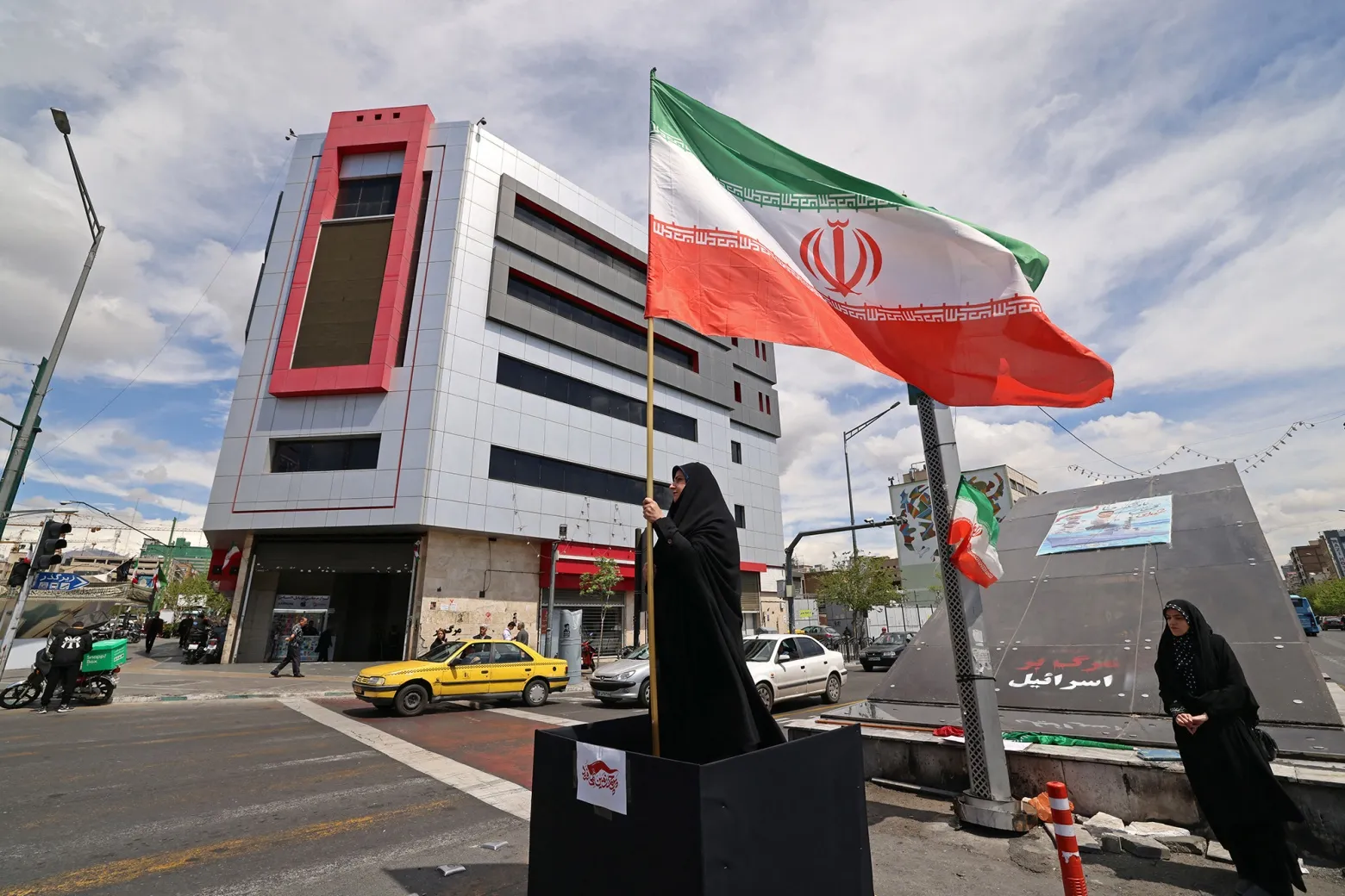 A woman stands with an Iranian national flag in Tehran on April 8.