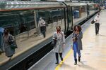 Commuters walk along the platform to board a Great Western Railway train, operated by FirstGroup Plc, at London Paddington railway station in London, U.K.