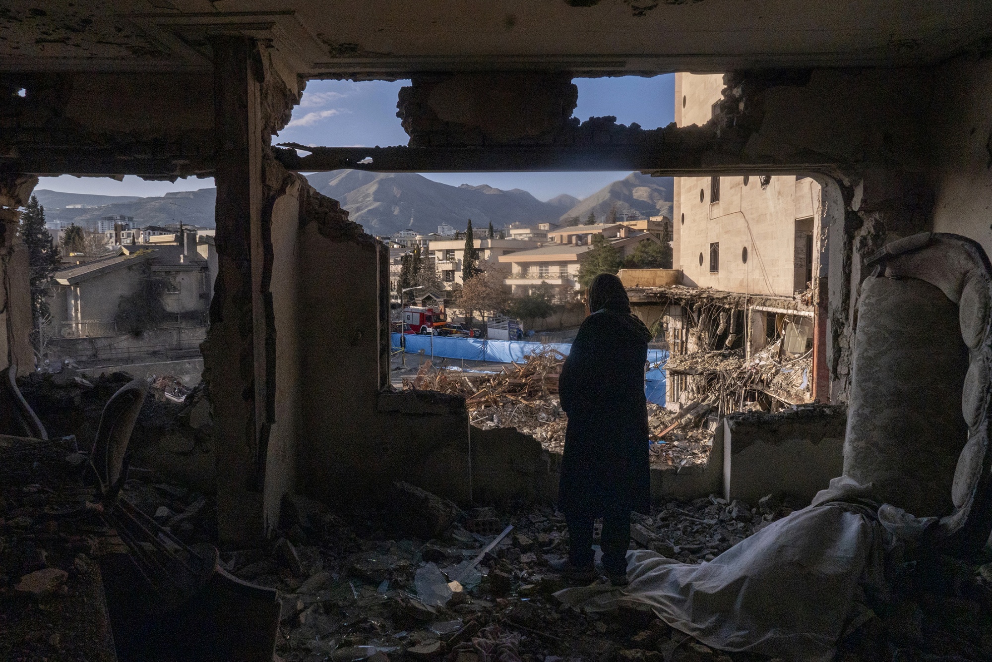 TEHRAN, IRAN - MARCH 21: A woman named Narges looks out from her destroyed apartment in the remains of a residential and commercial building on March 21, 2026 in the Shahrak-e Gharb neighbourhood of Tehran, Iran. The building was hit on March 16 amid U.S. and Israeli attacks and resulted in several civilian deaths and missing persons. The United States and Israel have continued their joint attack on Iran that began on February 28. Iran has retaliated by firing waves of missiles and drones at Israel, and targeting U.S. allies in the region. (Photo by Majid Saeedi/Getty Images) Photographer: Majid Saeedi/Getty Images Europe