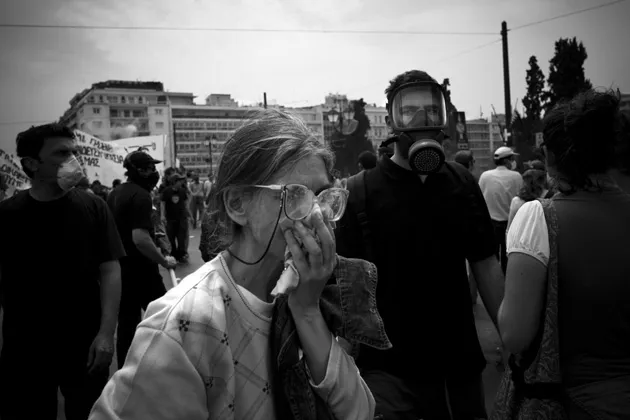 Protesters in Athens's Syntagma Square walk away from tear gas used by police during a demonstration against proposed austerity measures