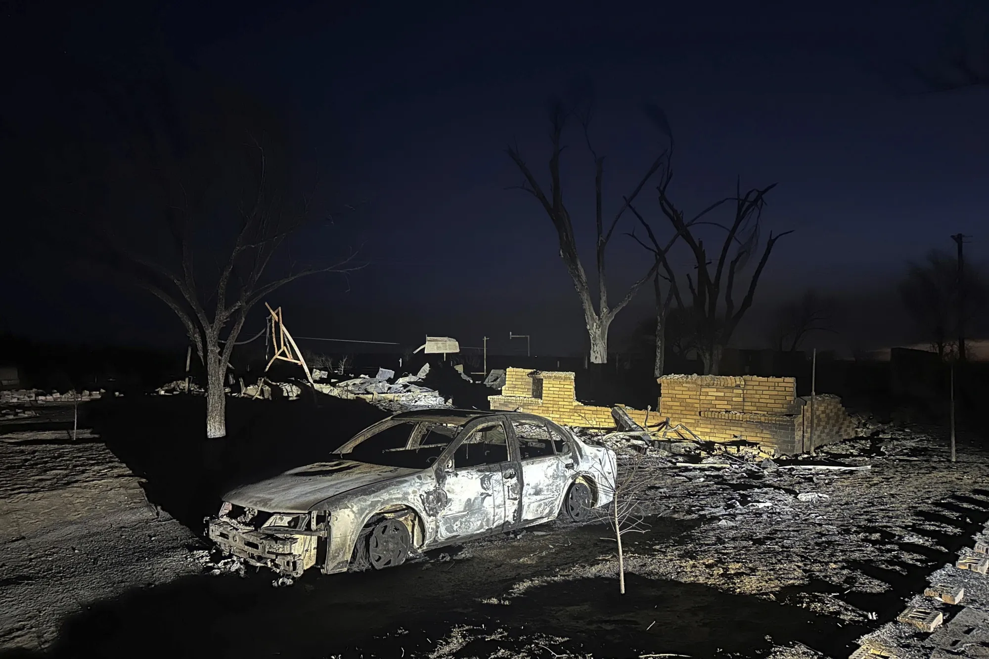A charred vehicle sits near the ruins of a home after the property was burned by the Smokehouse Creek Fire on&nbsp;Feb. 28.