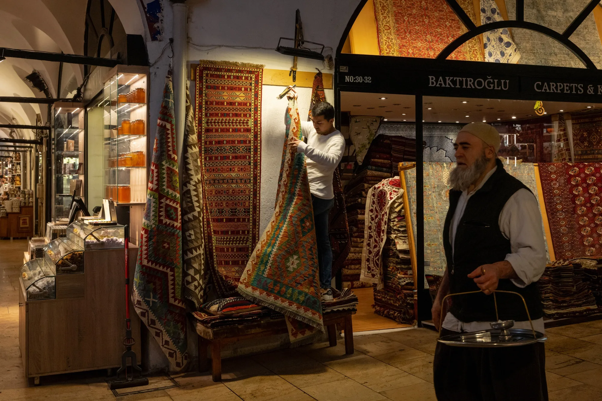 A shopkeeper hangs carpets outside his store at the Grand Bazaar in Istanbul.