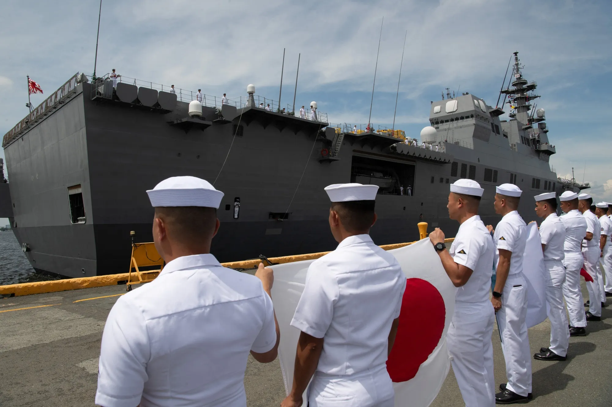 フィリピン海軍の乗組員が、海上自衛隊の「ひゅうが」型ヘリコプター護衛艦「いせ」号の前で日本の国旗を掲げている