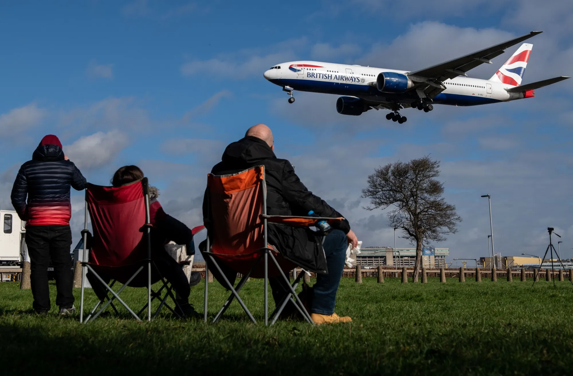 Plane spotters watch a British Airways airplane coming in to land at London Heathrow Airport.