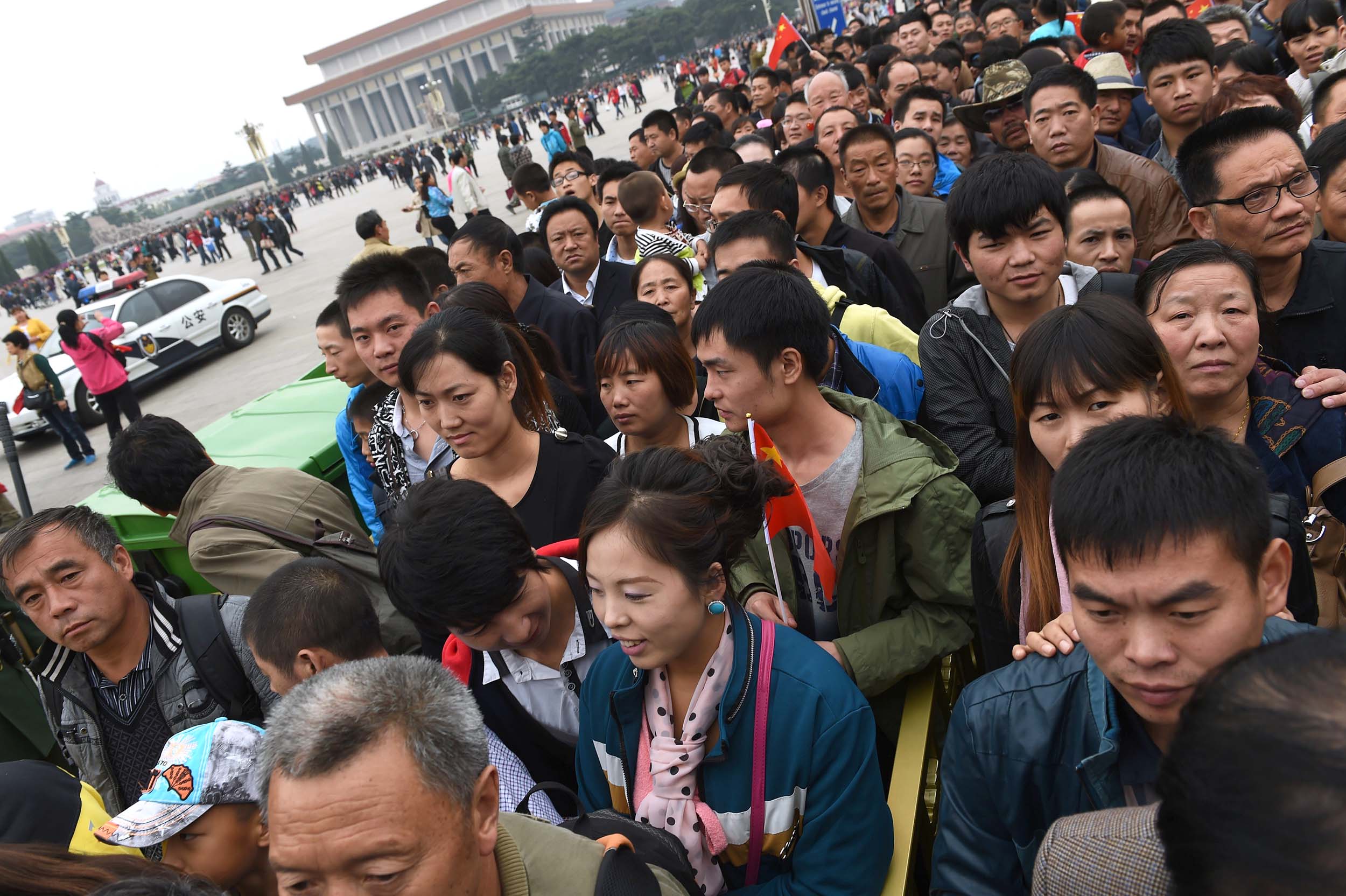 People wait to go through a security check at an entrance to Tiananmen Square, near the mausoleum of late communist leader Mao Zedong (top left) in Beijing on China's National Day.
