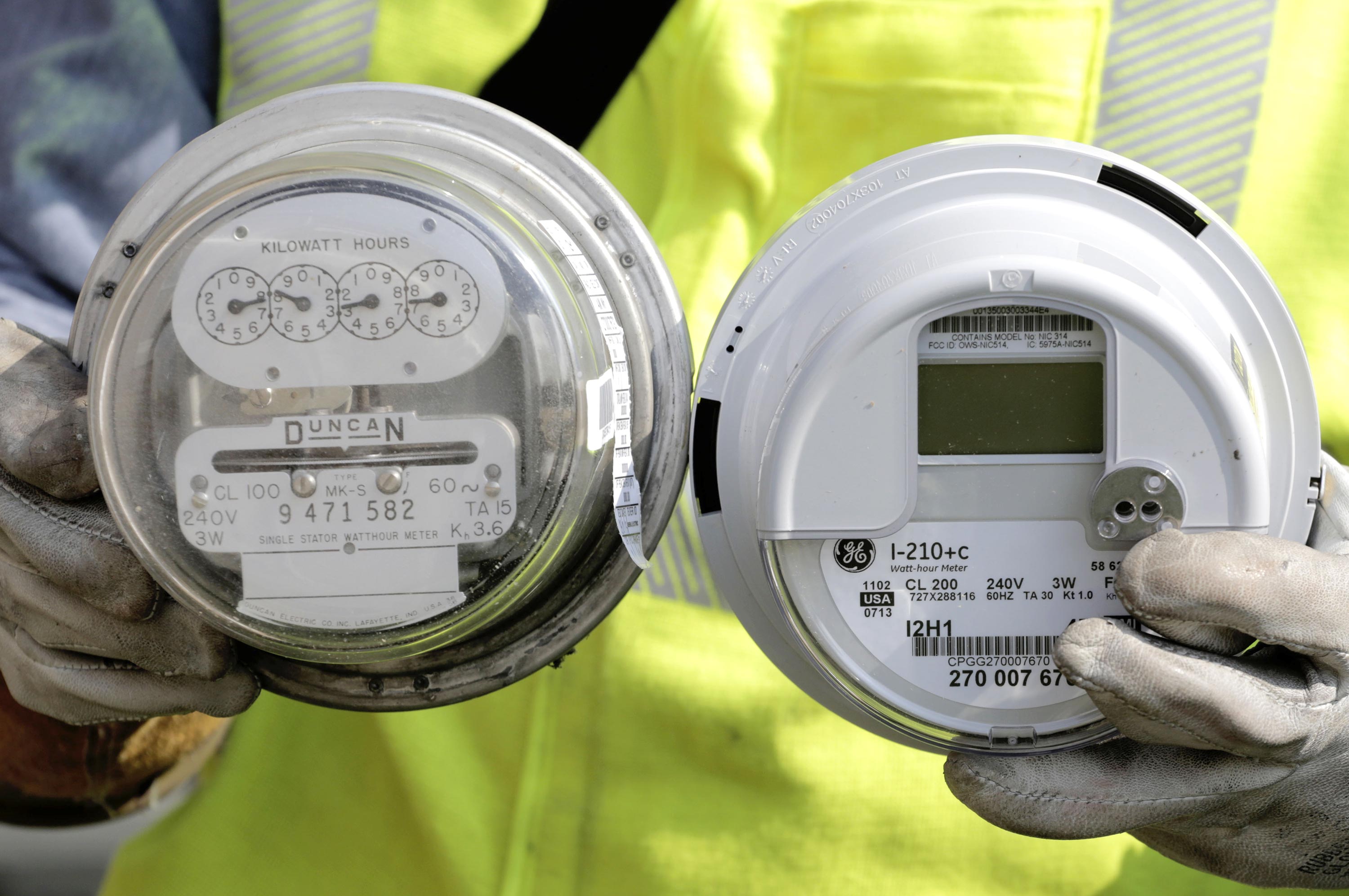 A senior energy technician for Commonwealth Edison holds a standard electricity meter, left, and a new &quot;smart&quot; meter in North Riverside, Ill. on Sept. 6, 2013. Photographer: M. Spencer Green/AP Photo
