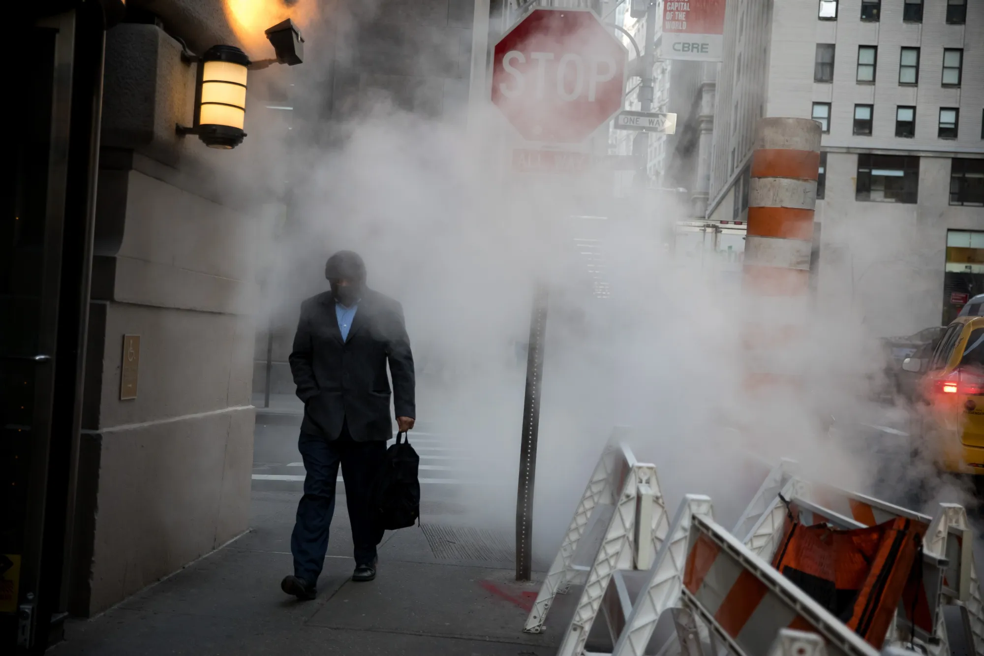 A pedestrian passes&nbsp;a tube releasing steam near the New York Stock Exchange.