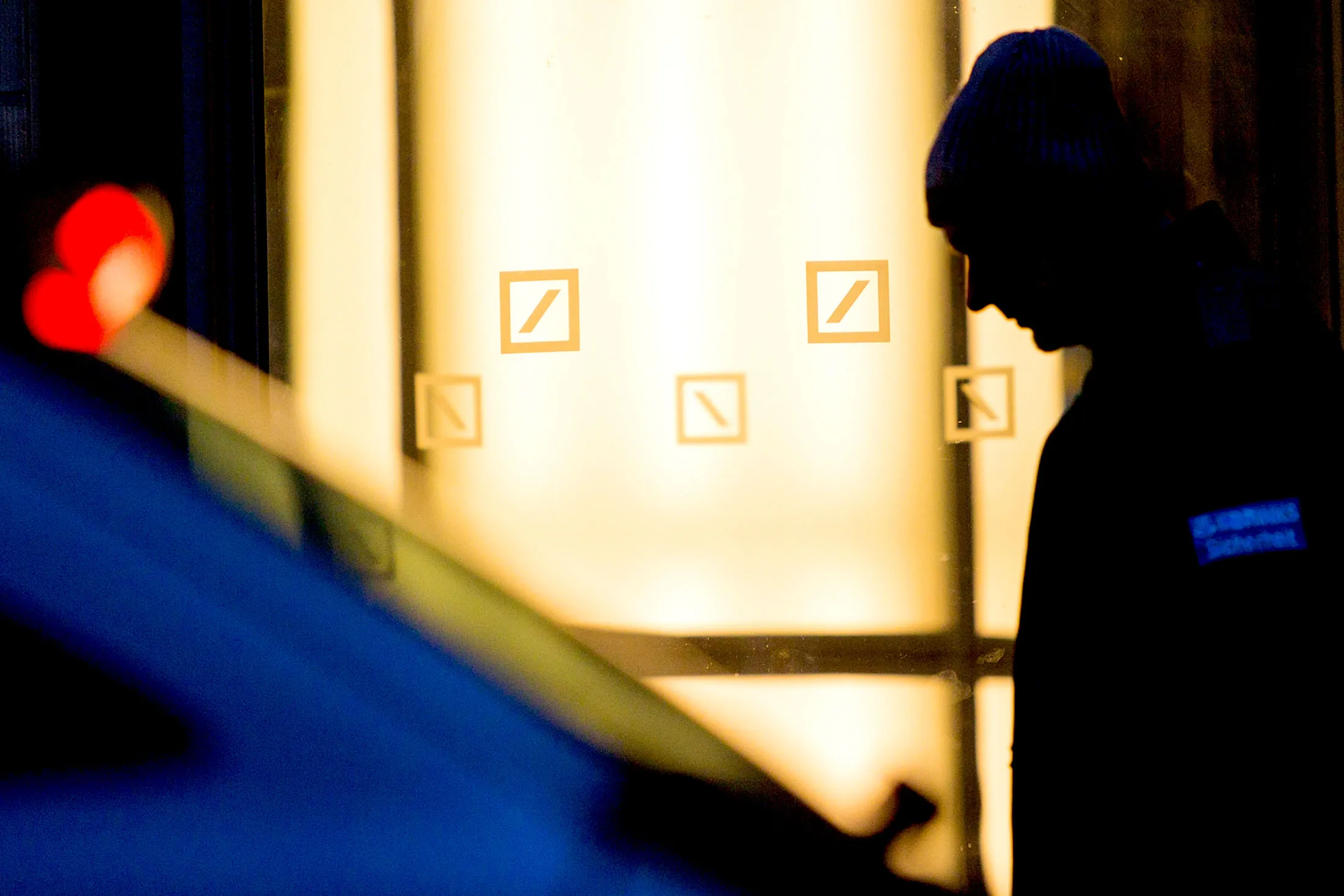 A pedestrian passes the offices of Deutsche Bank AG at dusk in Berlin.
