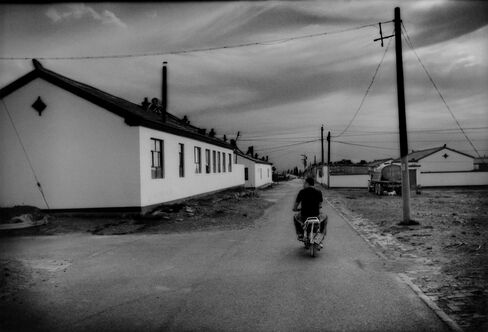 A Mongol man rides his motorbike into a government resettlement project, south of Bayanhaote.