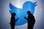 People are seen as silhouettes as they check mobile devices whilst standing against an illuminated wall bearing Twitter Inc.'s logo in this arranged photograph in London, U.K., on Tuesday, Jan. 5, 2016. Twitter Inc. may be preparing to raise its character limit for tweets to the thousands from the current 140, a person with knowledge of the matter said.