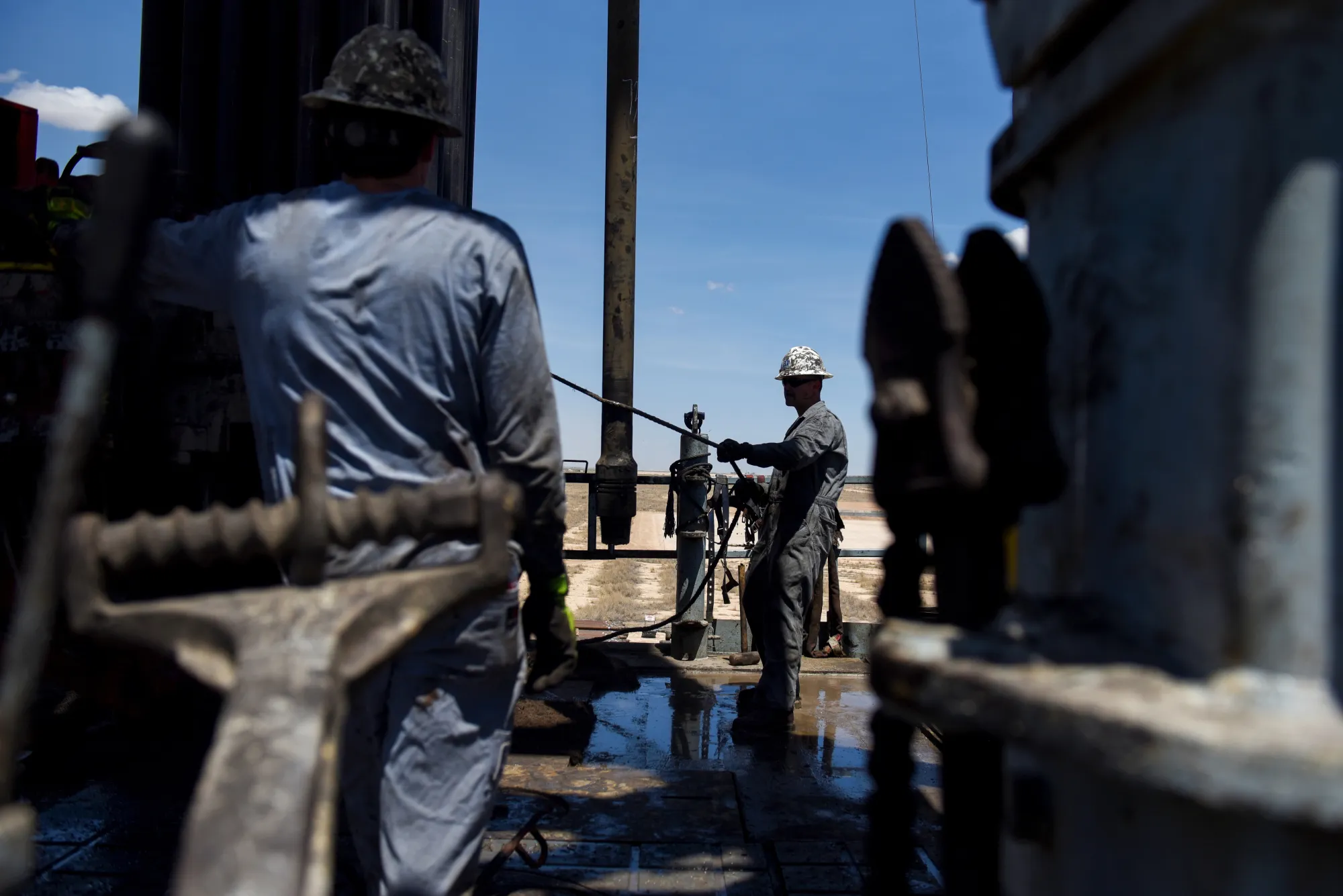 Contractors operate a drilling pipe at an oil rig in Reeves County, Texas.