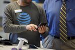 An employee helps a customer with a smartphone at an AT&amp;T Inc. store in Newport Beach, California.