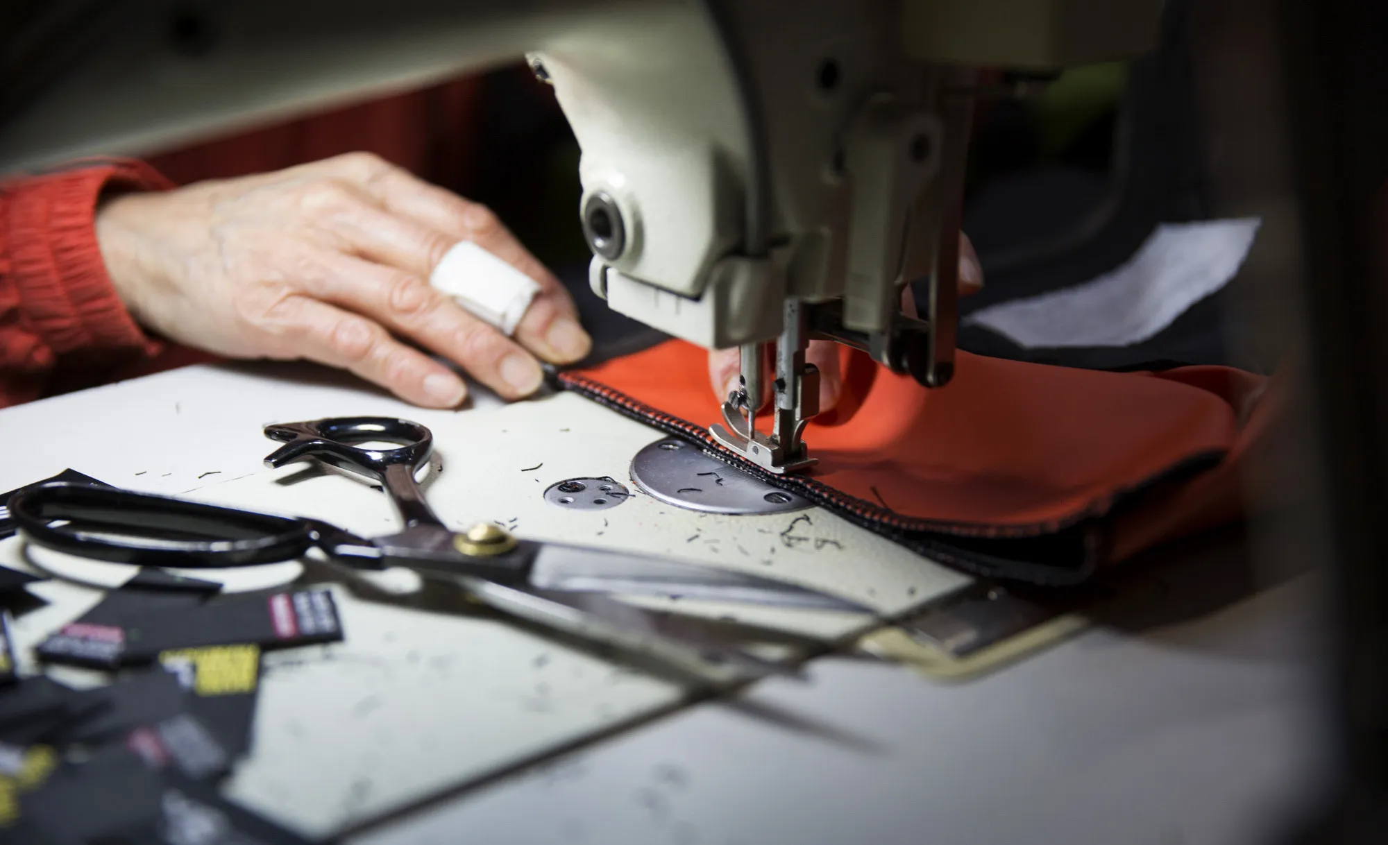 An employee sews fabric while assembling a backpack at a factory in San Francisco, California.