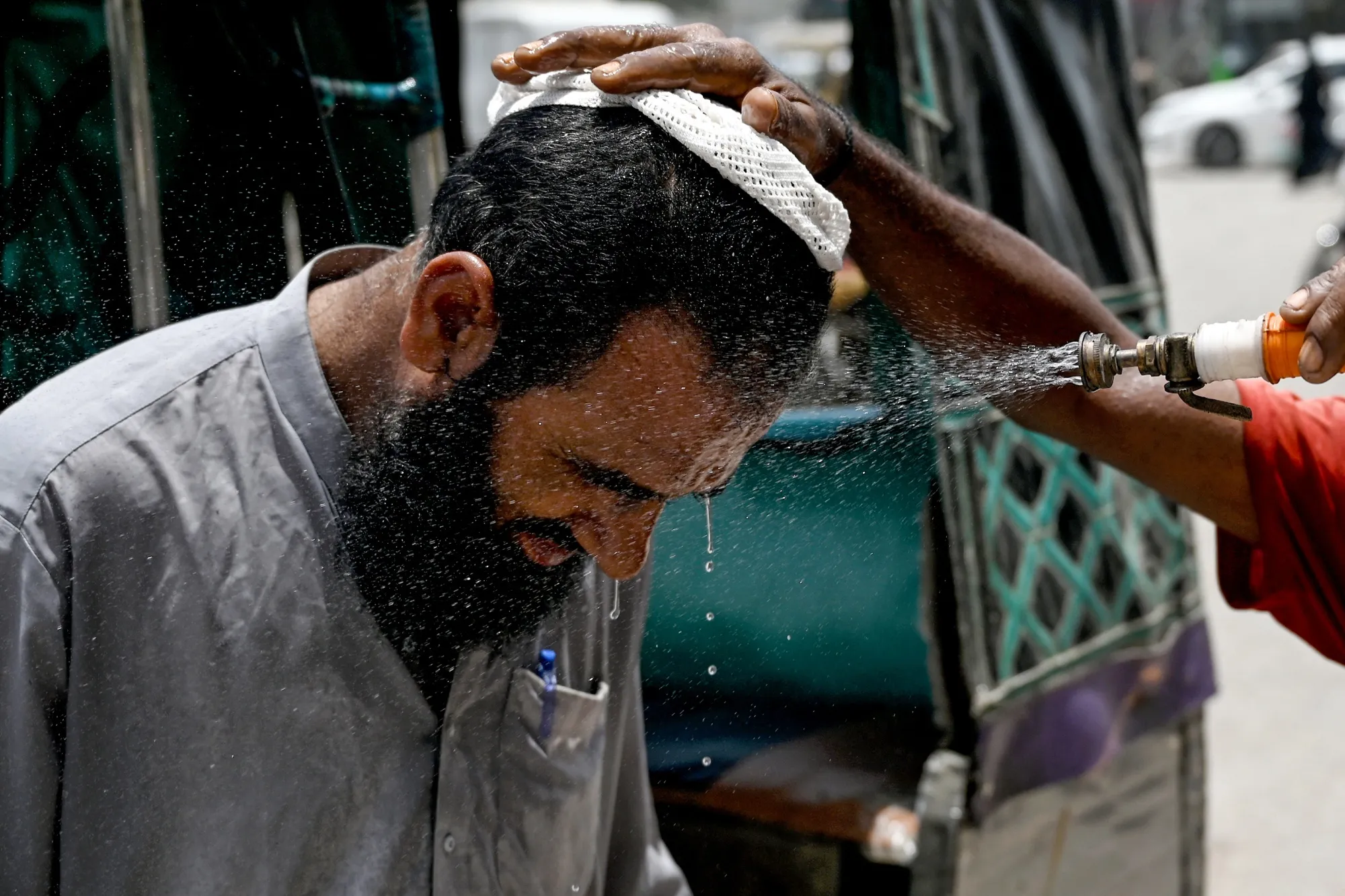A volunteer sprays water on a bypasser's face to cool off, in Karachi on June 24.