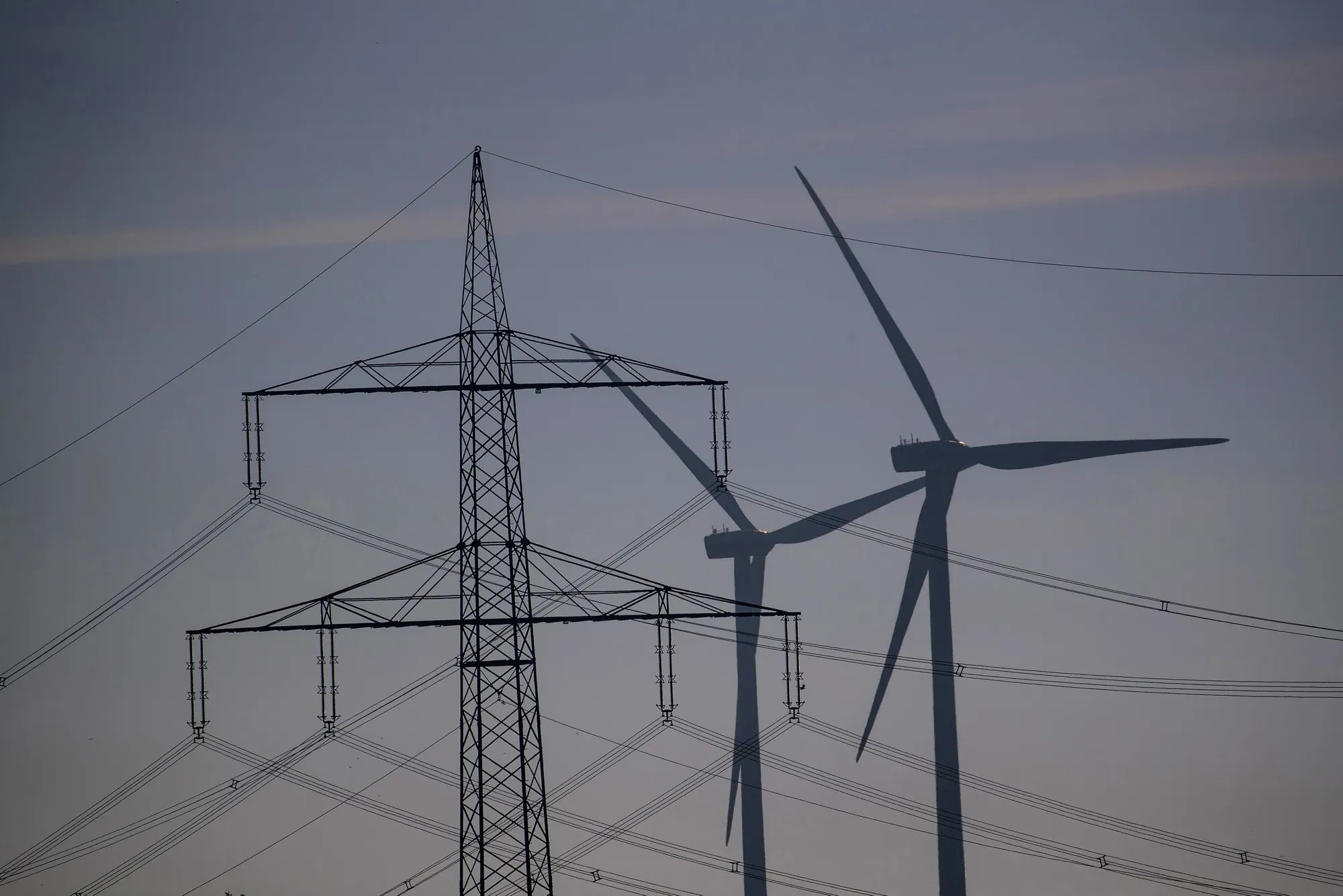 High voltage electricity power lines and wind turbines near Biegen, Germany.