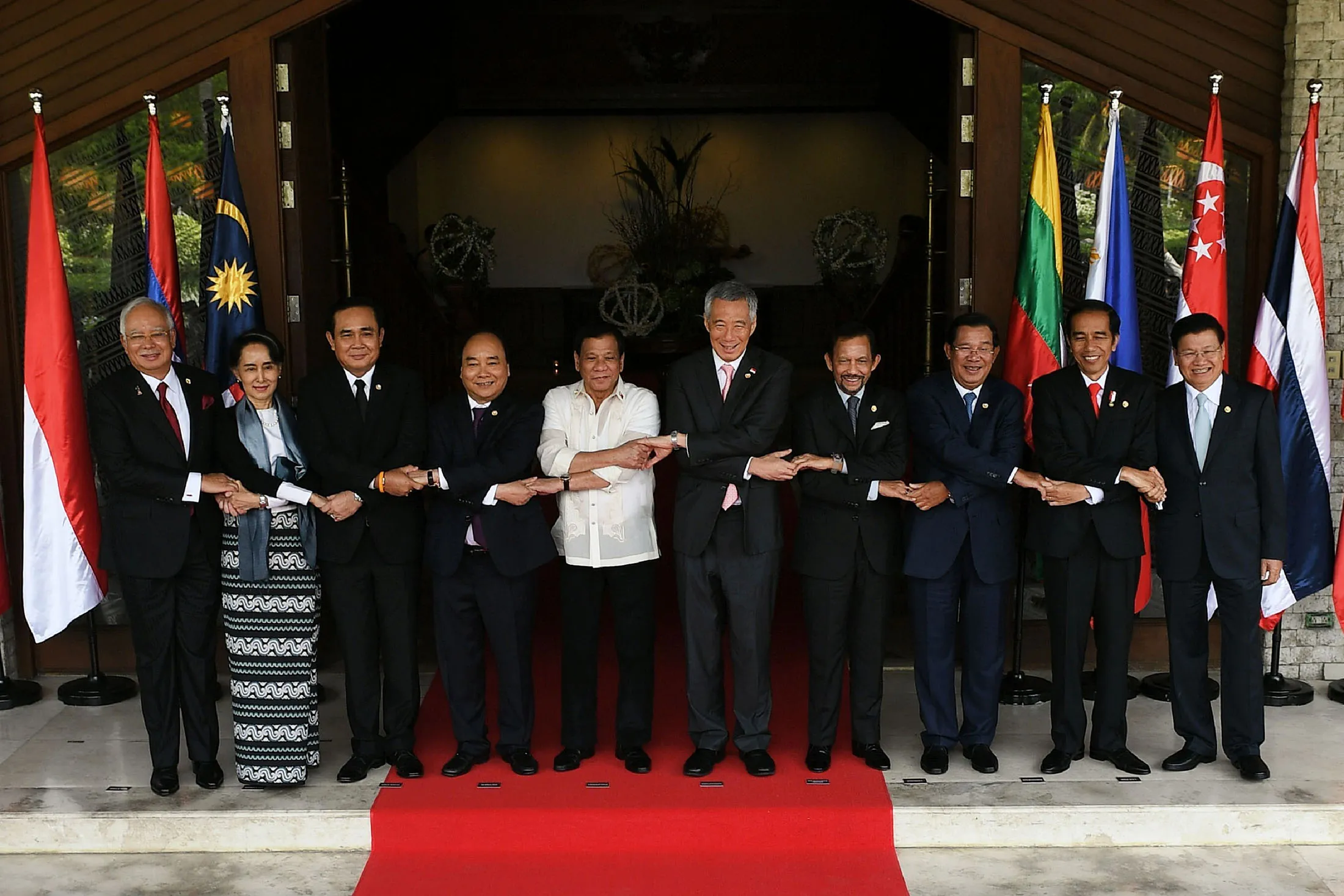 Malaysia's Prime Minister Najib Razak, from left to right, Myanmar's State Counsellor and Foreign Minister Aung San Suu Kyi, Thailand's Prime Minister Prayut Chan-O-Cha, Vietnam's Prime Minister Nguyen Xuan Phuc, Philippine President Rodrigo Duterte, Singapore's Prime Minister Lee Hsien Loong, Brunei Sultan Hassanal Bolkiah, Cambodia's Prime Minister Hun Sen, Indonesia's President Joko Widodo and Laos Prime Minister Thongloun Sisoulith join hands as they pose for a 'family photo' at Association of Southeast Asian Nations (ASEAN) leaders' summit in Manila on April 29, 2017.
