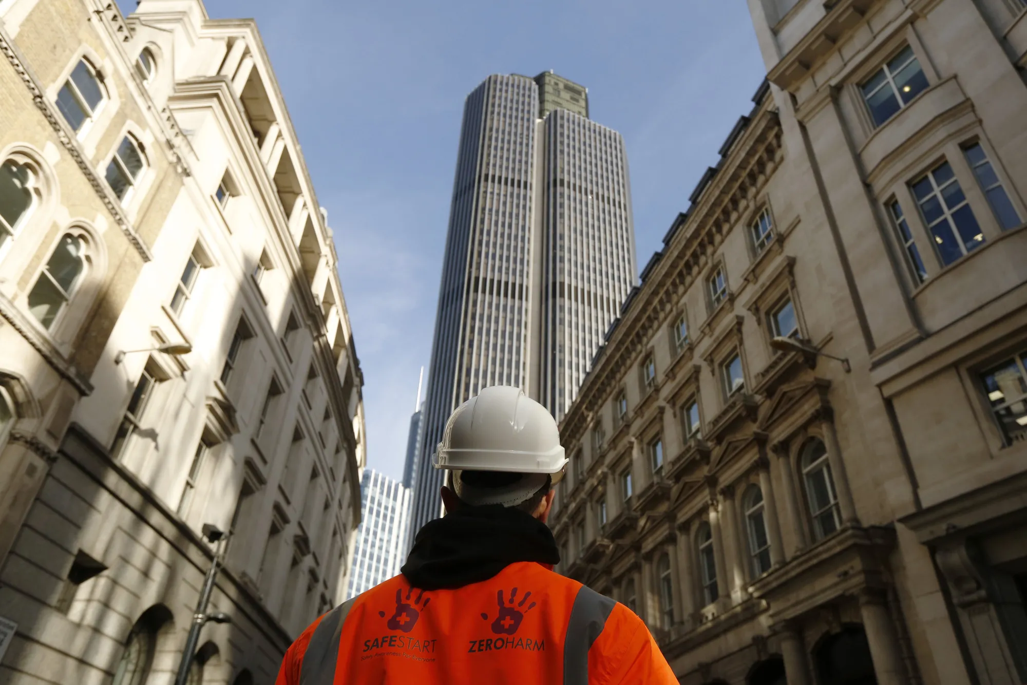 A construction worker looks toward a skyscraper&nbsp;in&nbsp;London.