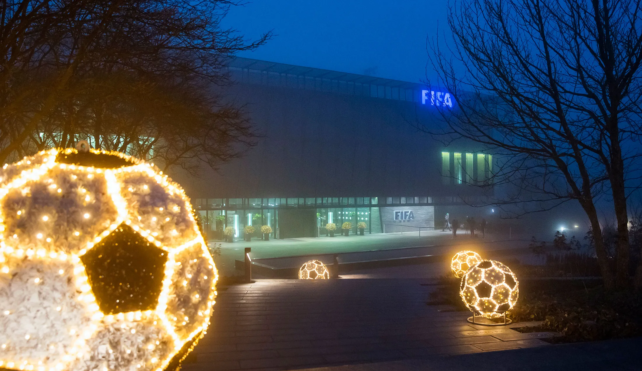 Football artwork installations sit illuminated outside the FIFA headquarters following an Executive Committee meeting in Zurich
