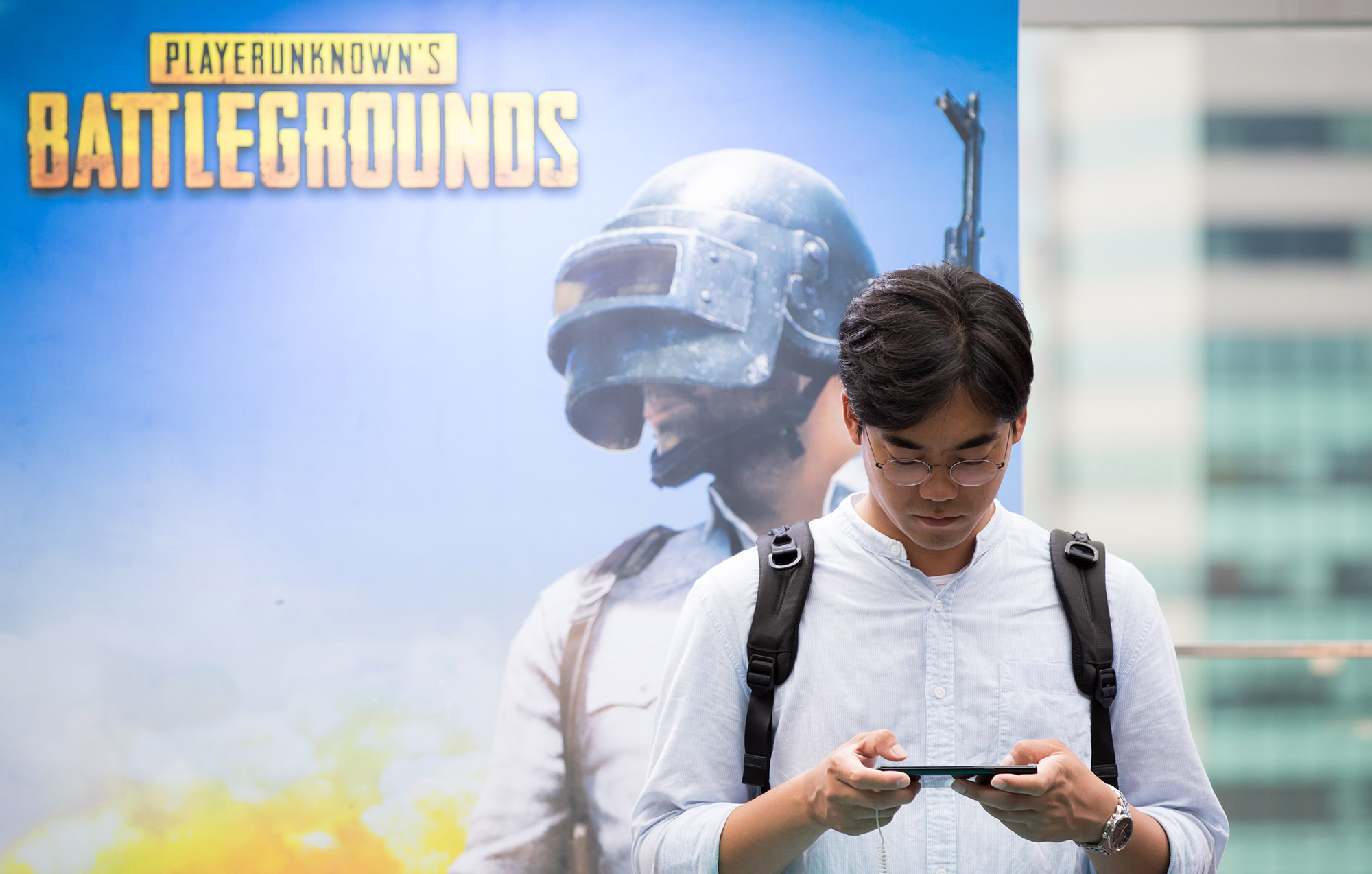 A person uses a smartphone in front of a poster of the PlayerUnknown's Battlegrounds game&nbsp;in Seoul.