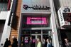 Pedestrians pass in front of a T-Mobile US Inc. store in New York, U.S.