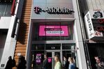 Pedestrians pass in front of a T-Mobile US Inc. store in New York, U.S.