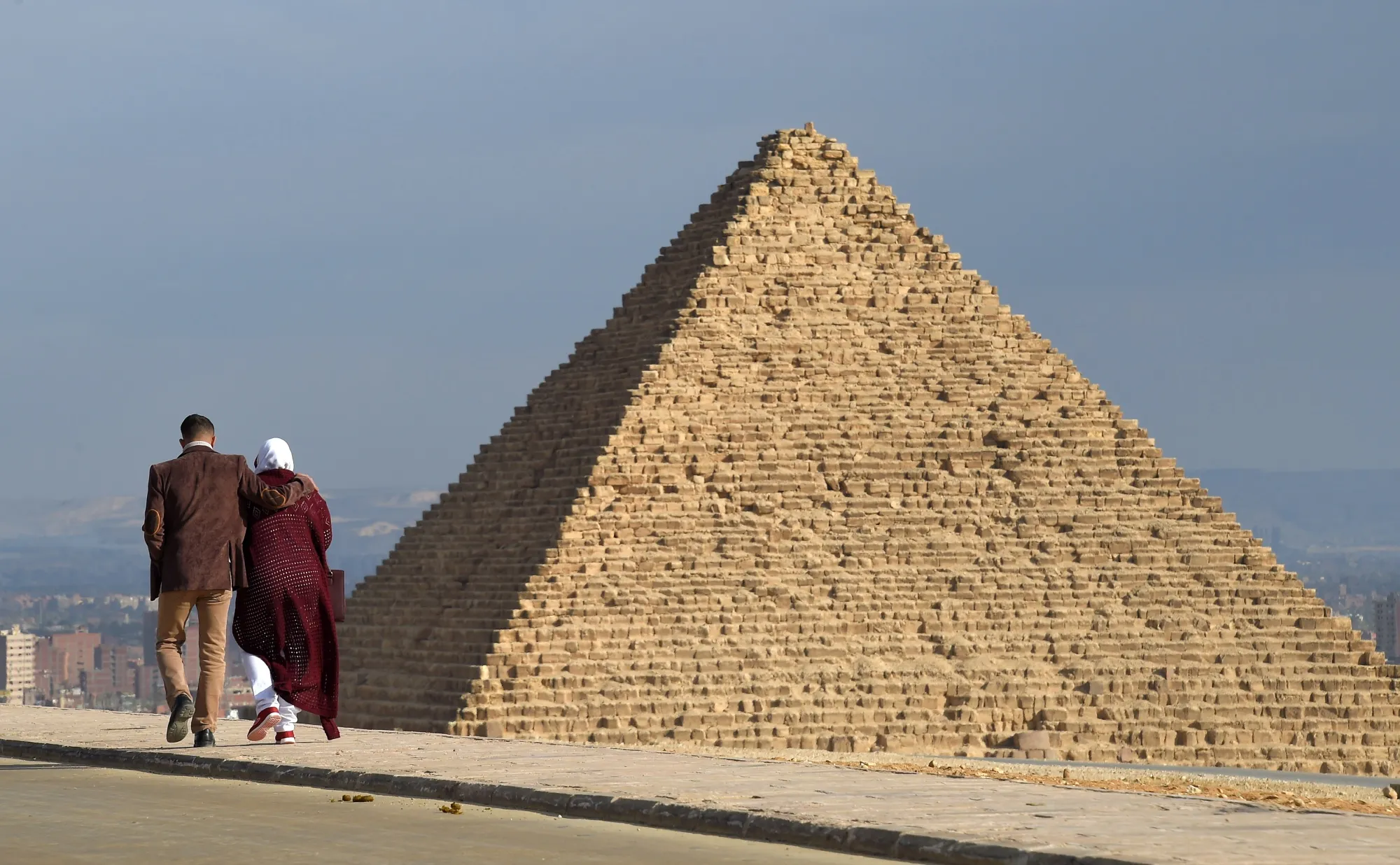A couple walk along a road at the Giza pyramids necropolis on the southwestern outskirts of the Egyptian capital Cairo.