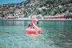 Happy girl on flamingo floating on clear water in Nice,France