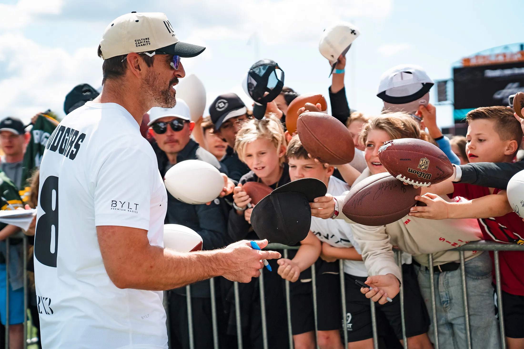 New York Jets quarterback Aaron Rodgers signing autographs during a charity flag football tournament.